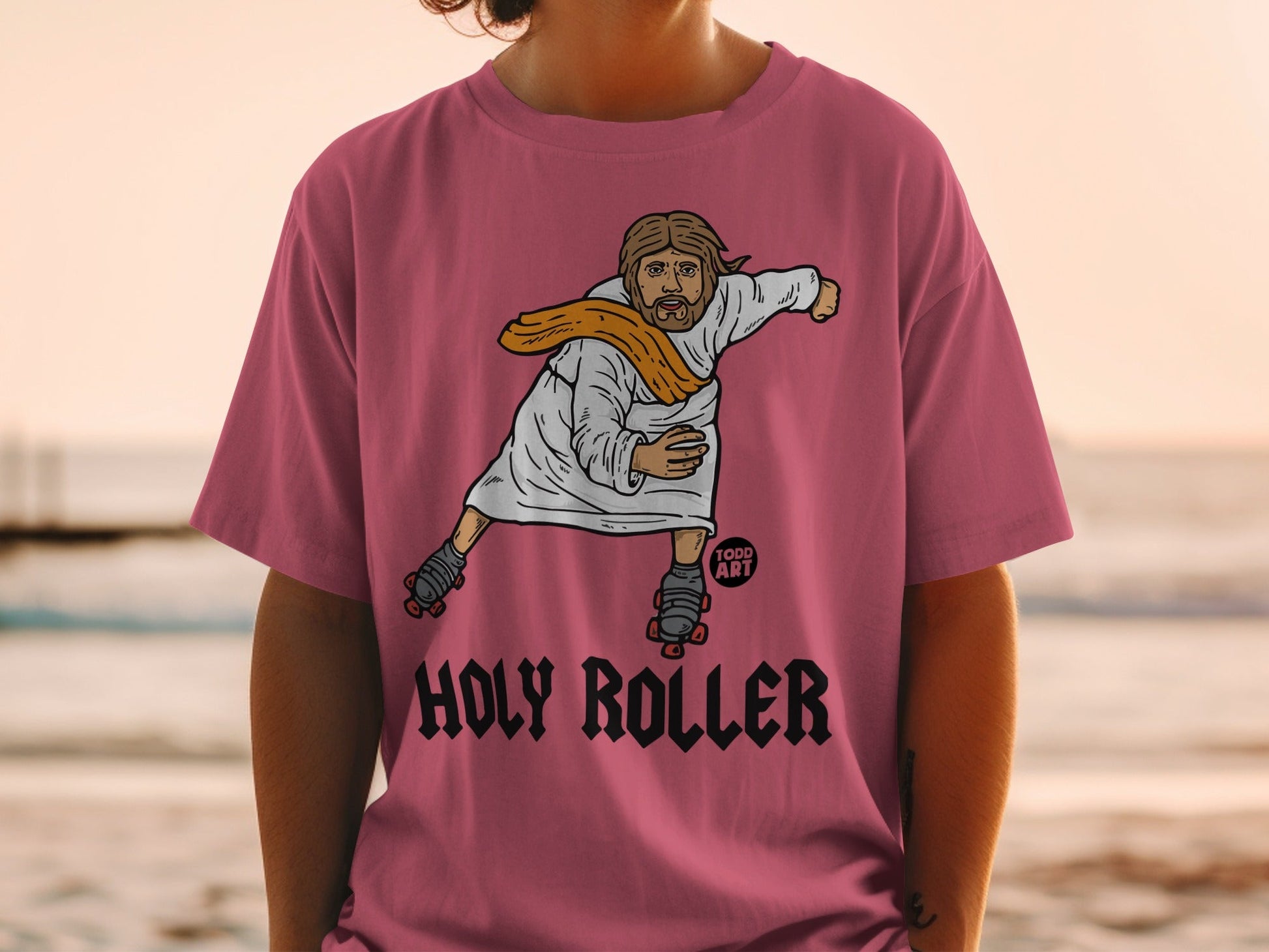 Jesus on roller skates wearing a pink t-shirt with "Holy Roller" text.