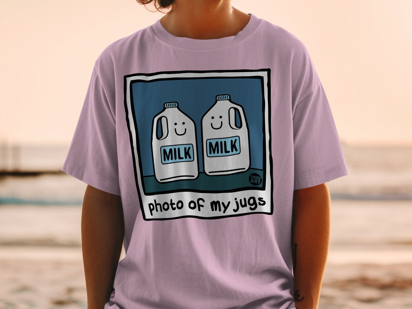 Pink t-shirt with a graphic of two smiling milk jugs and text reading "photo of my jugs."
