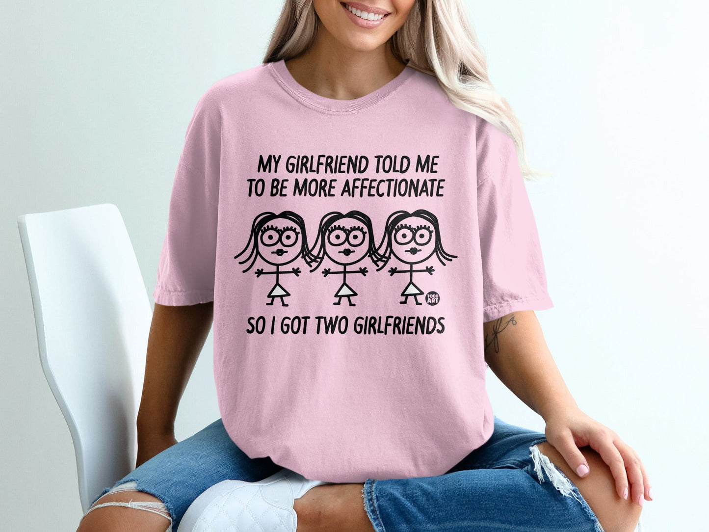 Pink t-shirt with cartoon women and text: "My girlfriend told me to be more affectionate, so I got two girlfriends."