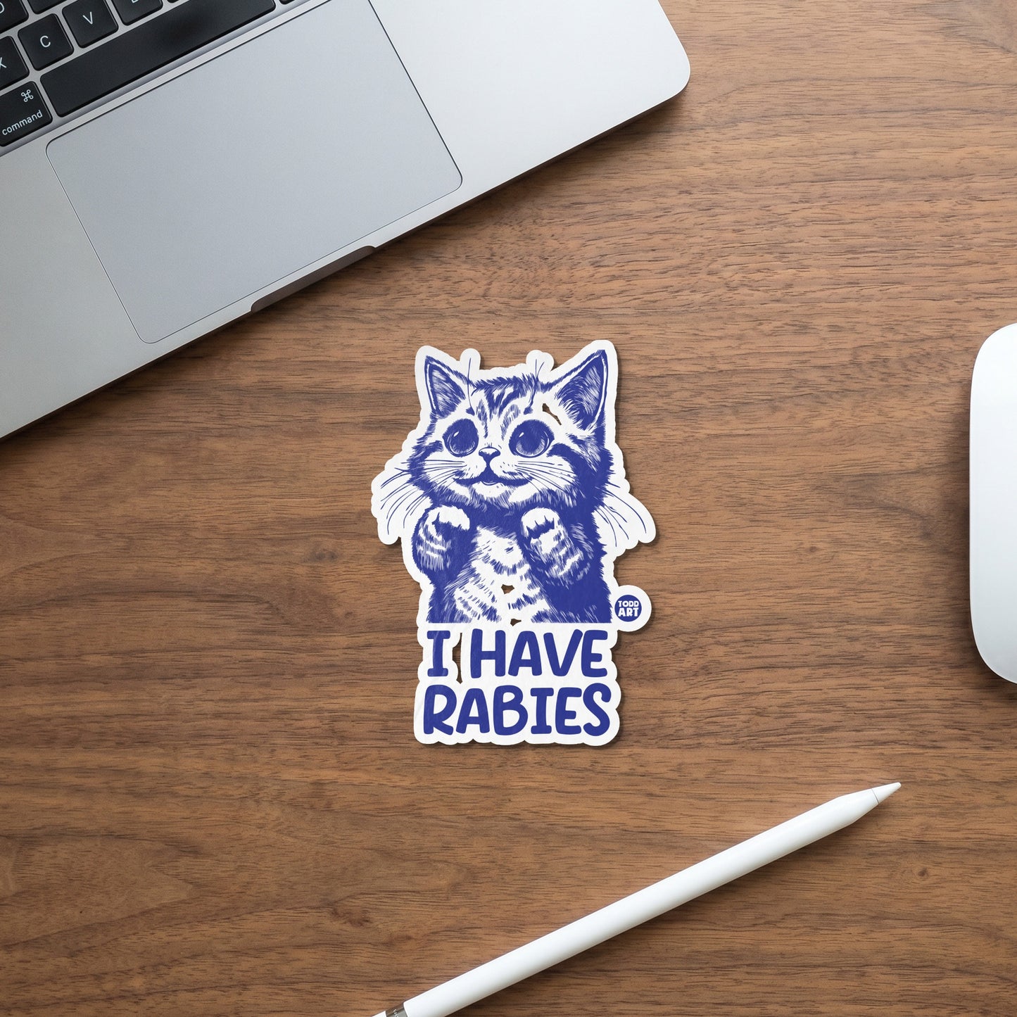 Blue ink sticker of a cat with text "I HAVE RABIES" on a wooden surface.