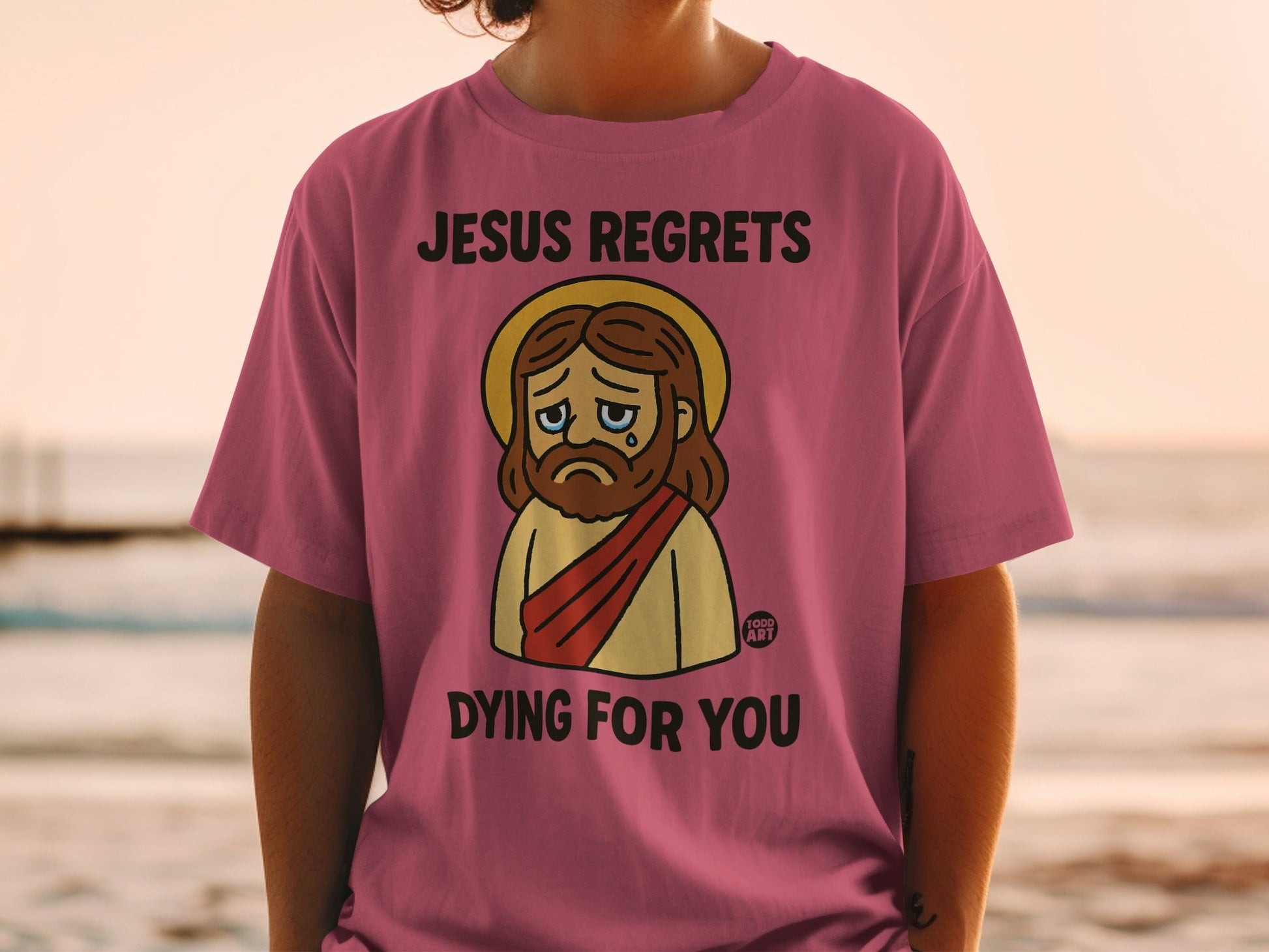 Pink t-shirt with Jesus graphic and text "JESUS REGRETS DYING FOR YOU".