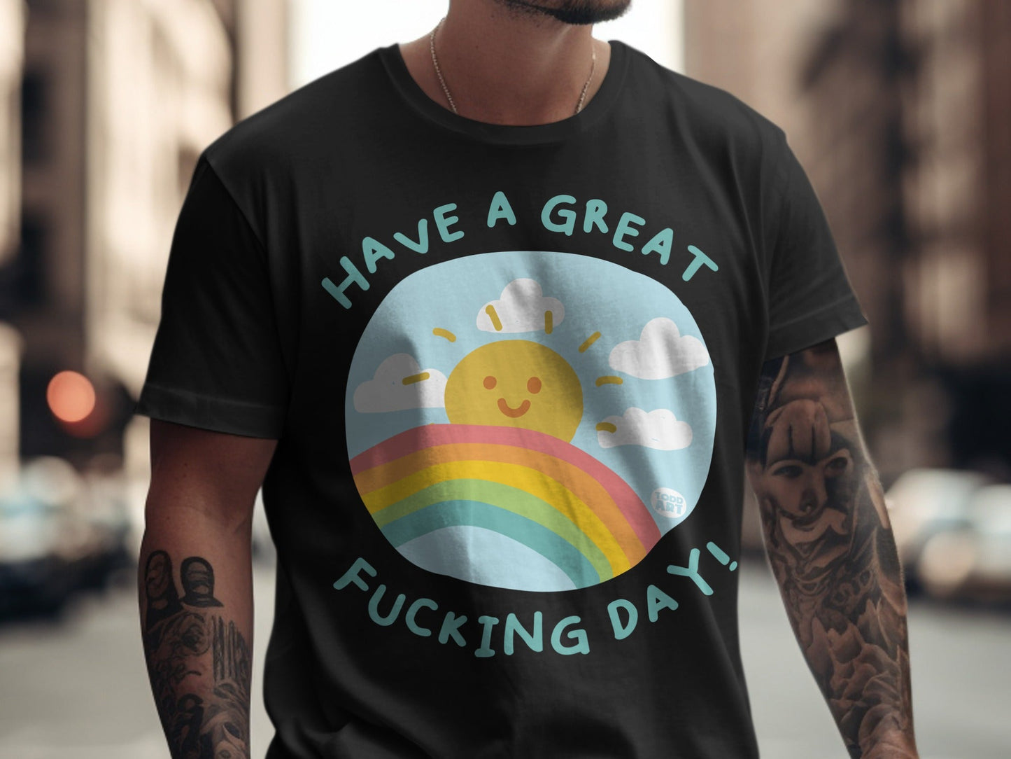 Black t-shirt with a graphic of a smiling sun over a rainbow and text "HAVE A GREAT FUCKING DAY!".
