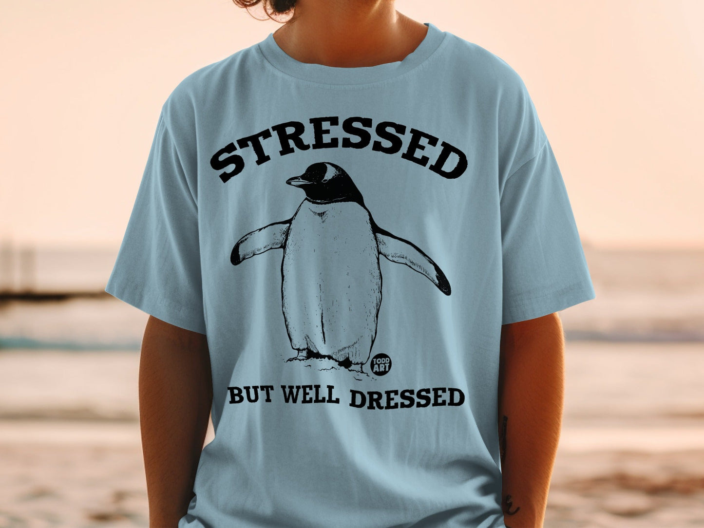 T-shirt with penguin graphic and text "STRESSED BUT WELL DRESSED".