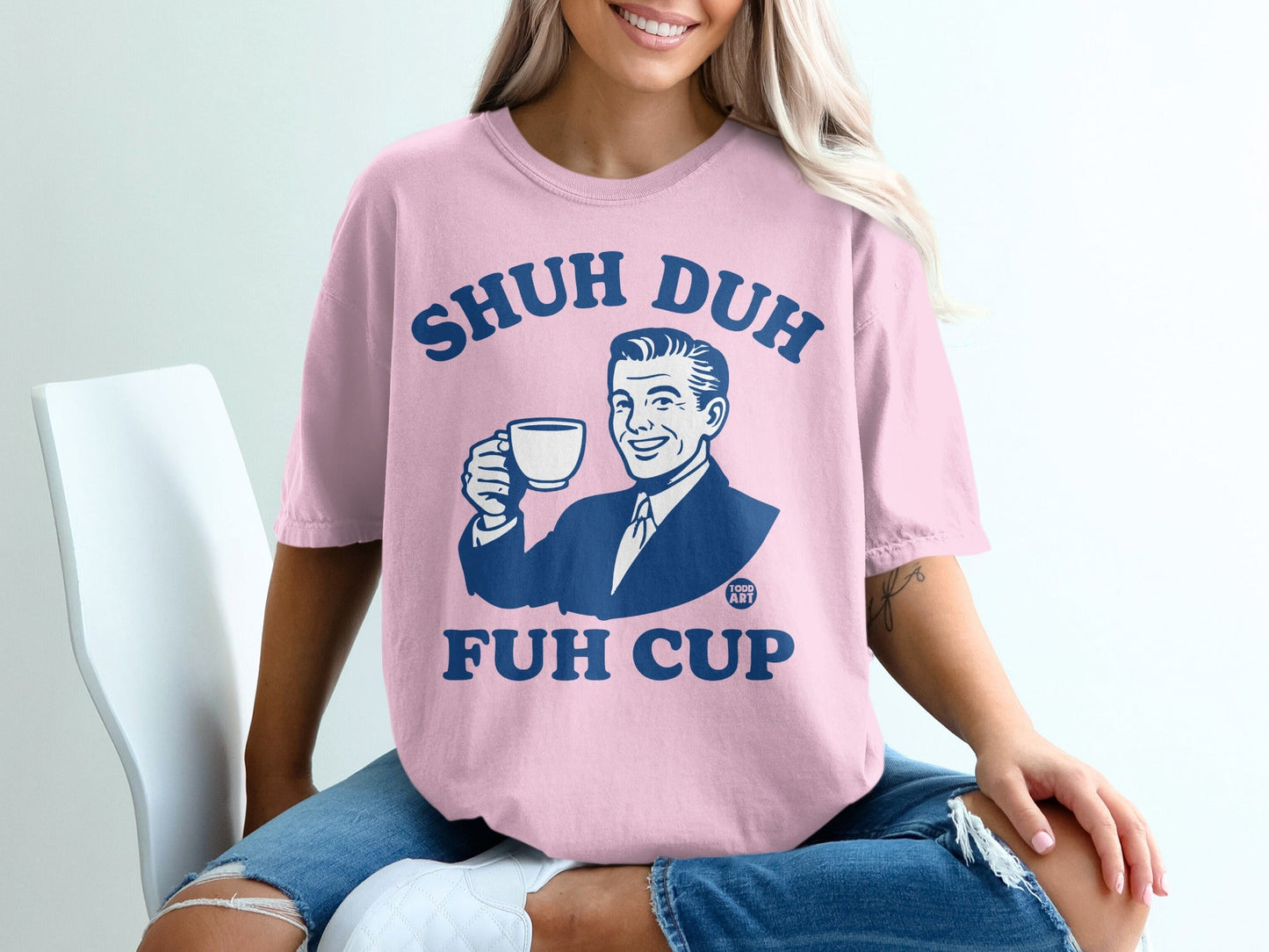 Pink t-shirt with "Shuh Duh Fuh Cup" text and retro cartoon man holding coffee.