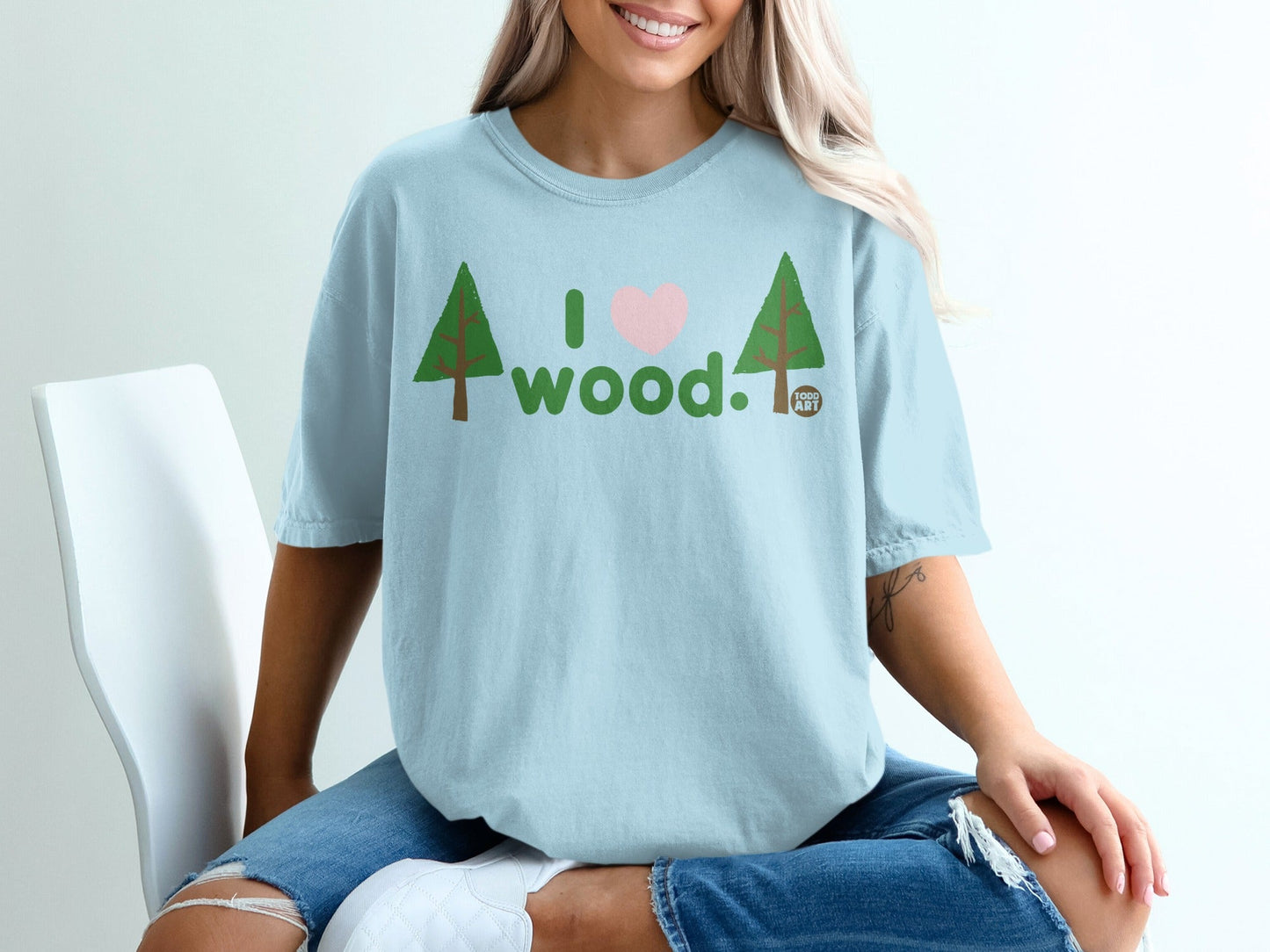 Light blue t-shirt with pink heart and "I love wood" text, trees.