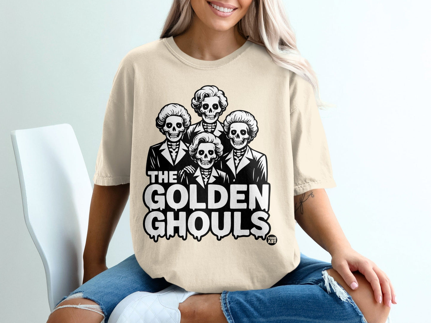 Cream t-shirt with "The Golden Ghouls" text and skeleton portraits.