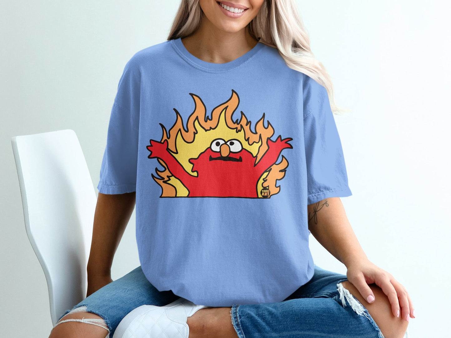 Elmo character from Sesame Street on fire, wearing a light blue t-shirt.