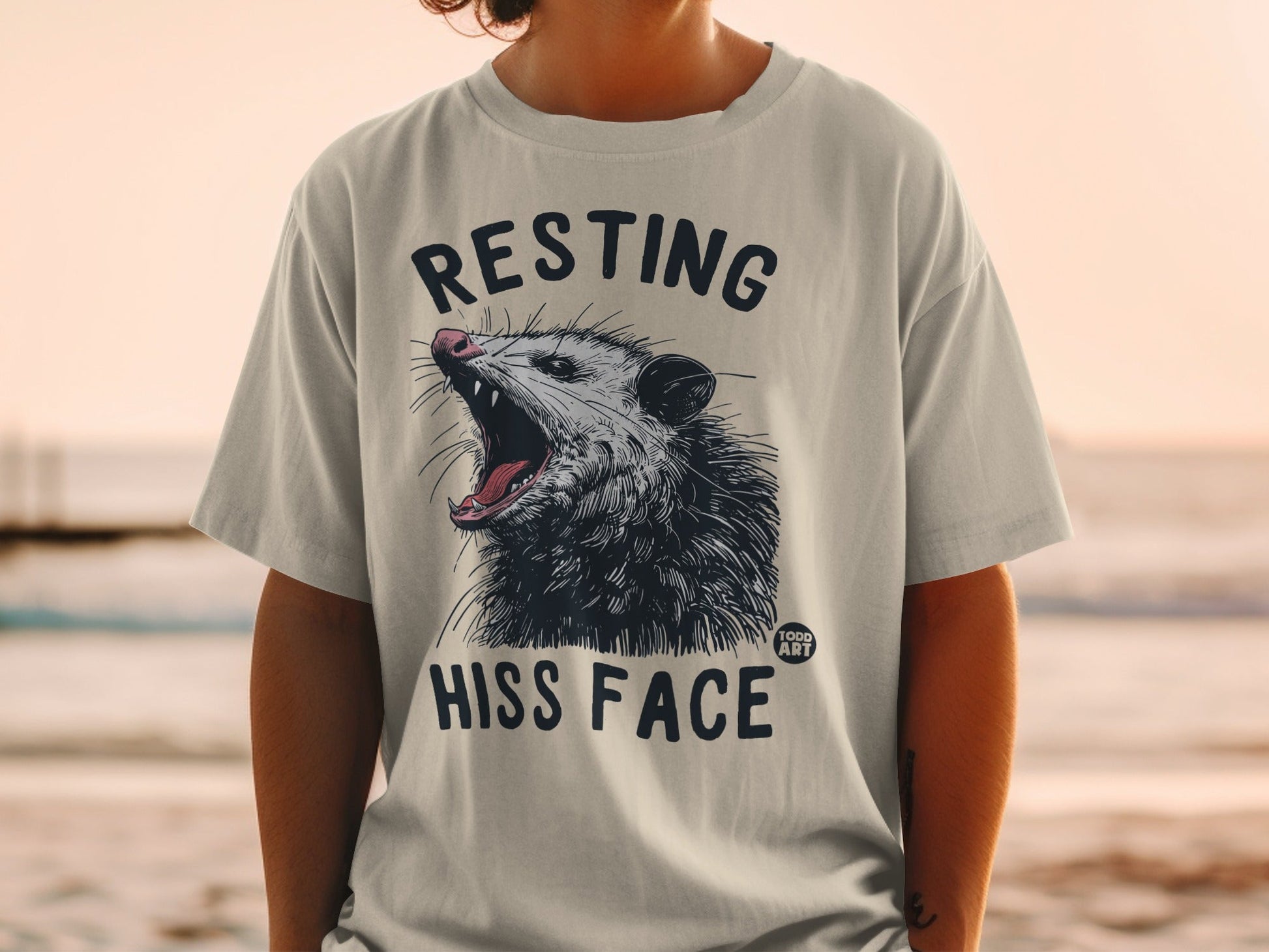 T-shirt with a possum graphic and text "RESTING HISS FACE."