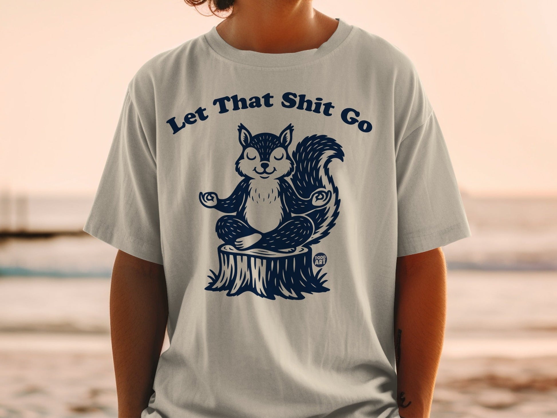 T-shirt with a meditating squirrel sitting on a tree stump, text reads "Let That Shit Go."