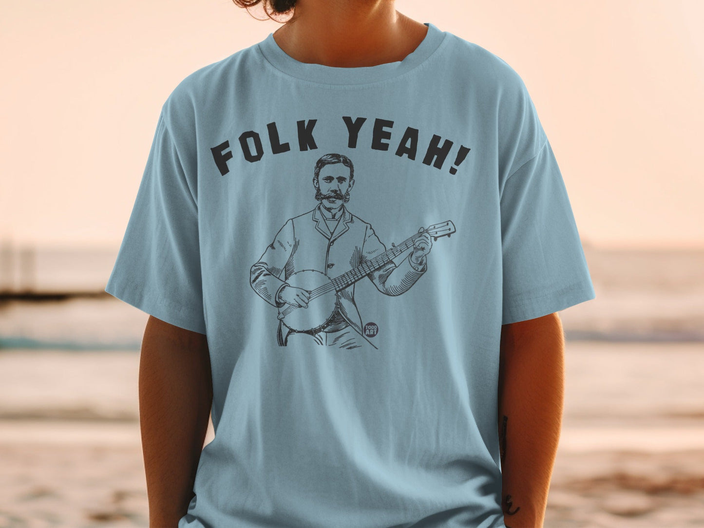 Light blue t-shirt with "Folk Yeah!" text and a man playing a banjo.
