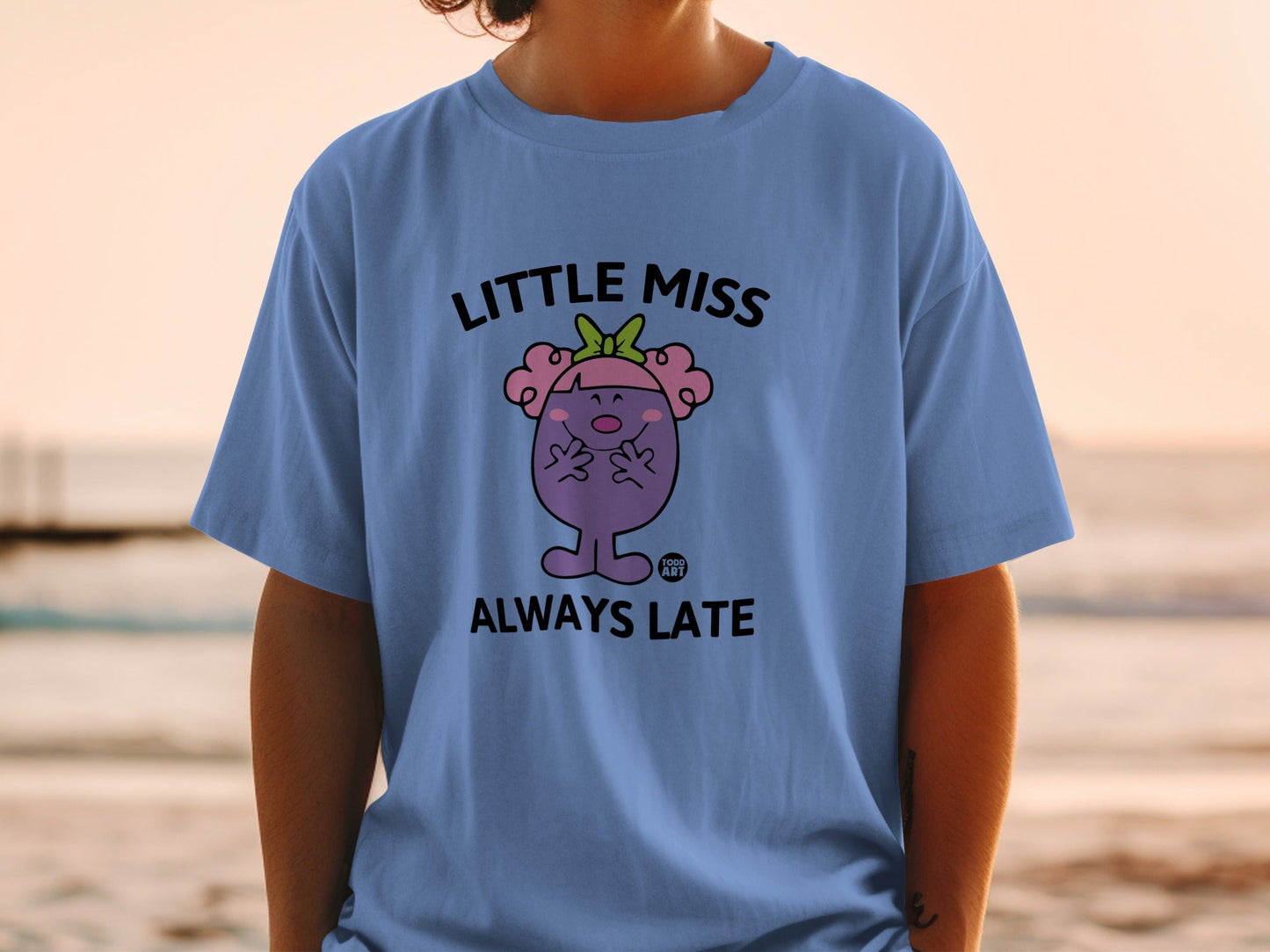 Little Miss Always Late cartoon character on a blue t-shirt.