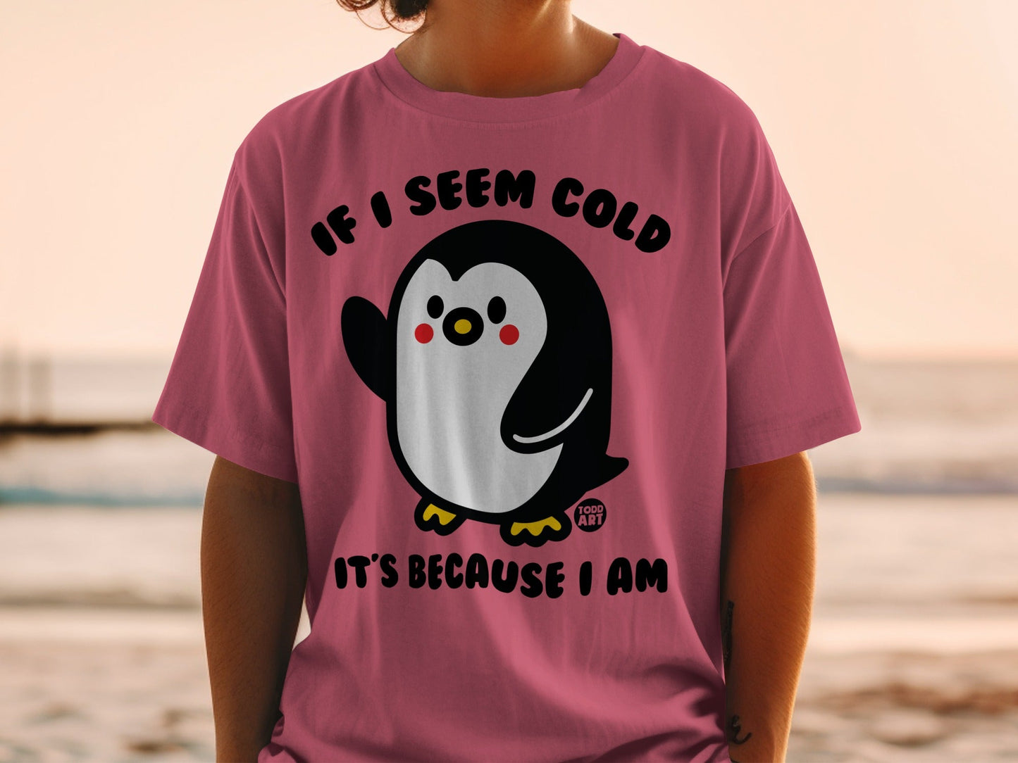 Pink t-shirt with a penguin graphic and text "IF I SEEM COLD IT'S BECAUSE I AM".