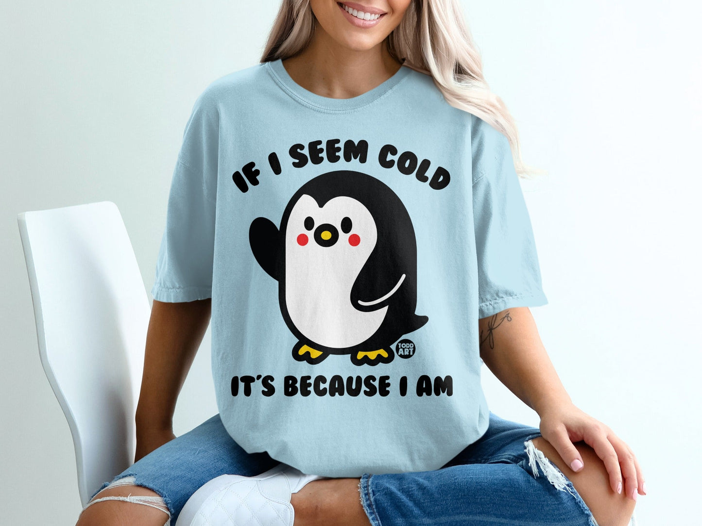 Light blue t-shirt with a waving cartoon penguin and the text "IF I SEEM COLD IT'S BECAUSE I AM".