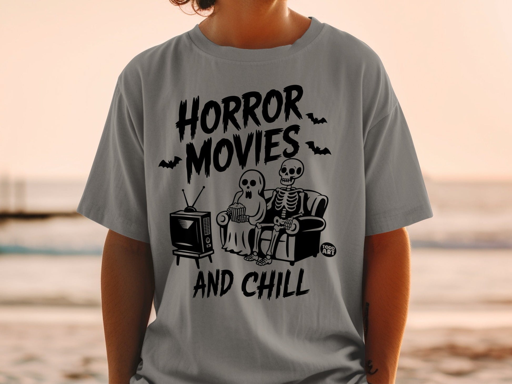 Gray t-shirt with "Horror Movies and Chill" text, skeleton couple watching TV.