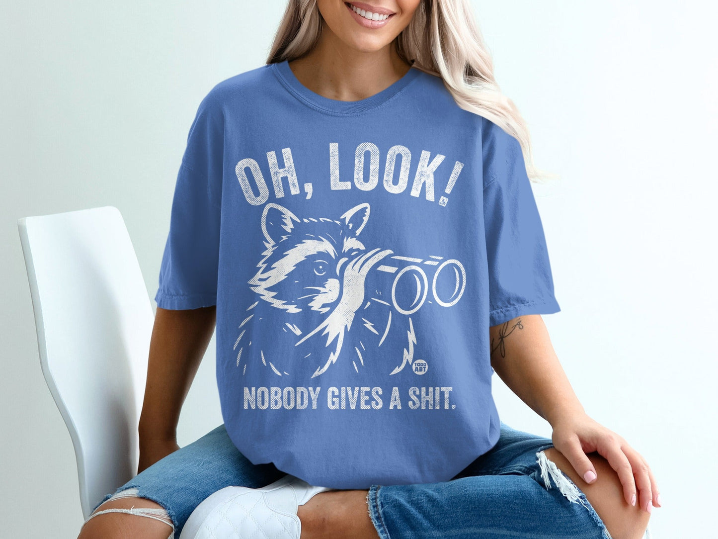 Blue t-shirt with raccoon holding binoculars and text "OH, LOOK! NOBODY GIVES A SHIT."