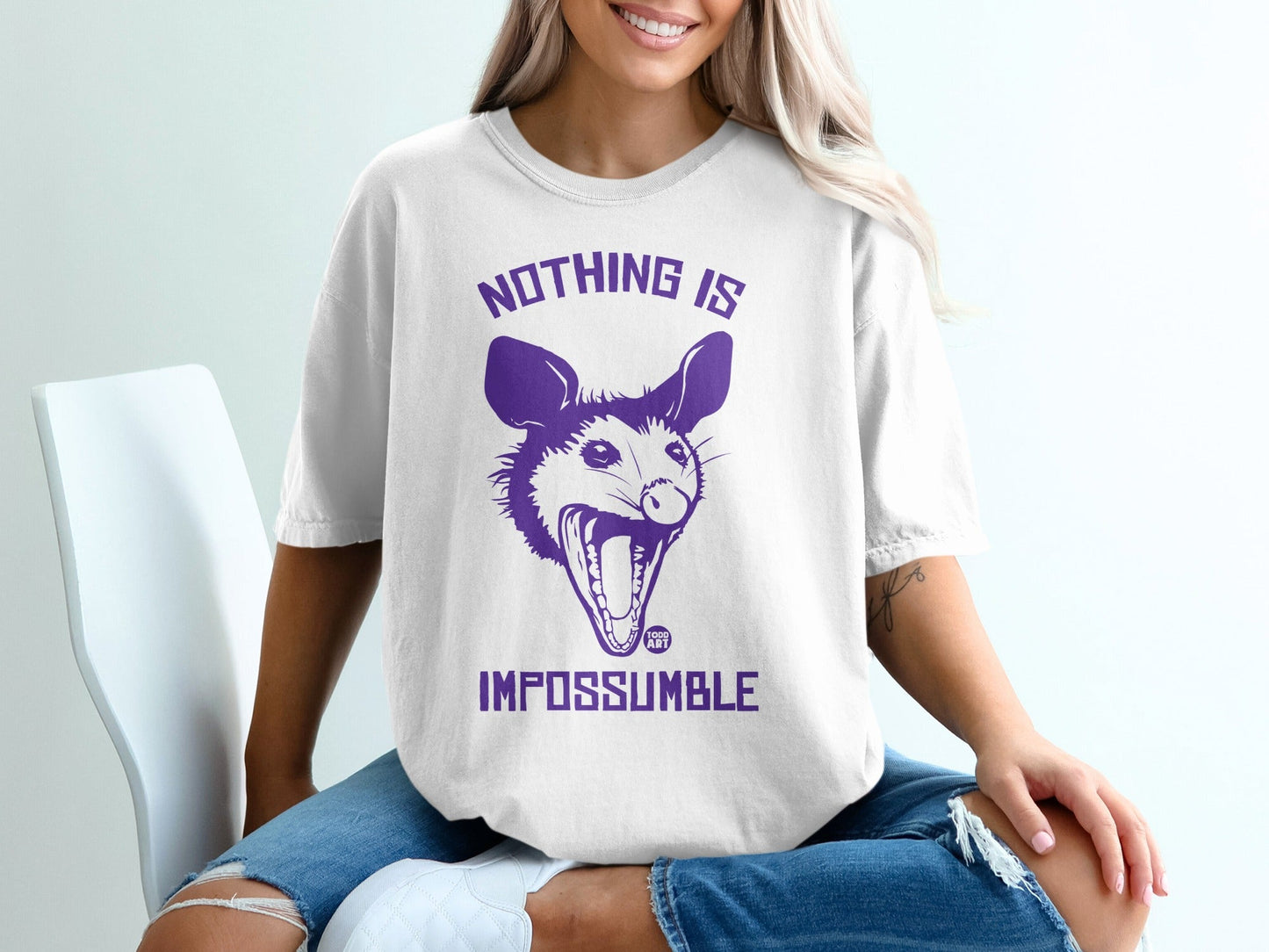 White t-shirt with purple opossum graphic and text "NOTHING IS IMPOSSUMBLE".