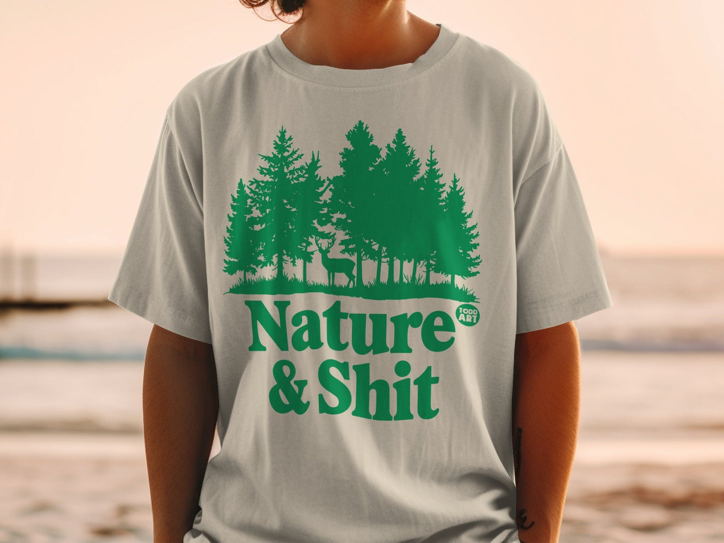 Green t-shirt with forest and deer graphic, and "Nature & Shit" text.