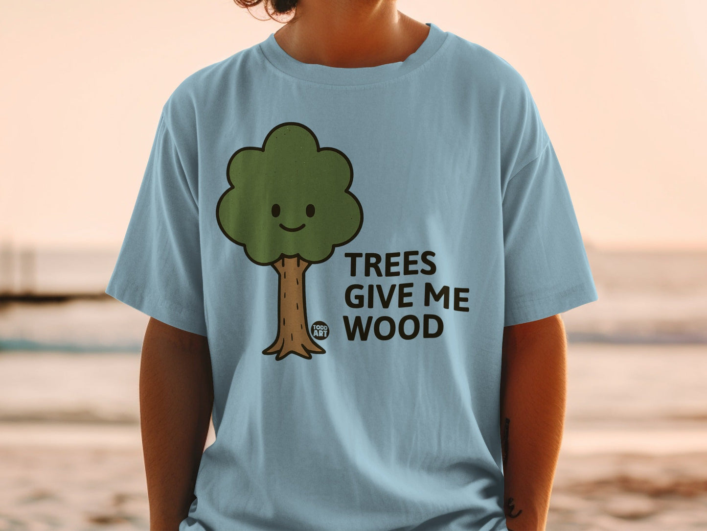 Light blue t-shirt with smiling cartoon tree graphic and text "TREES GIVE ME WOOD".