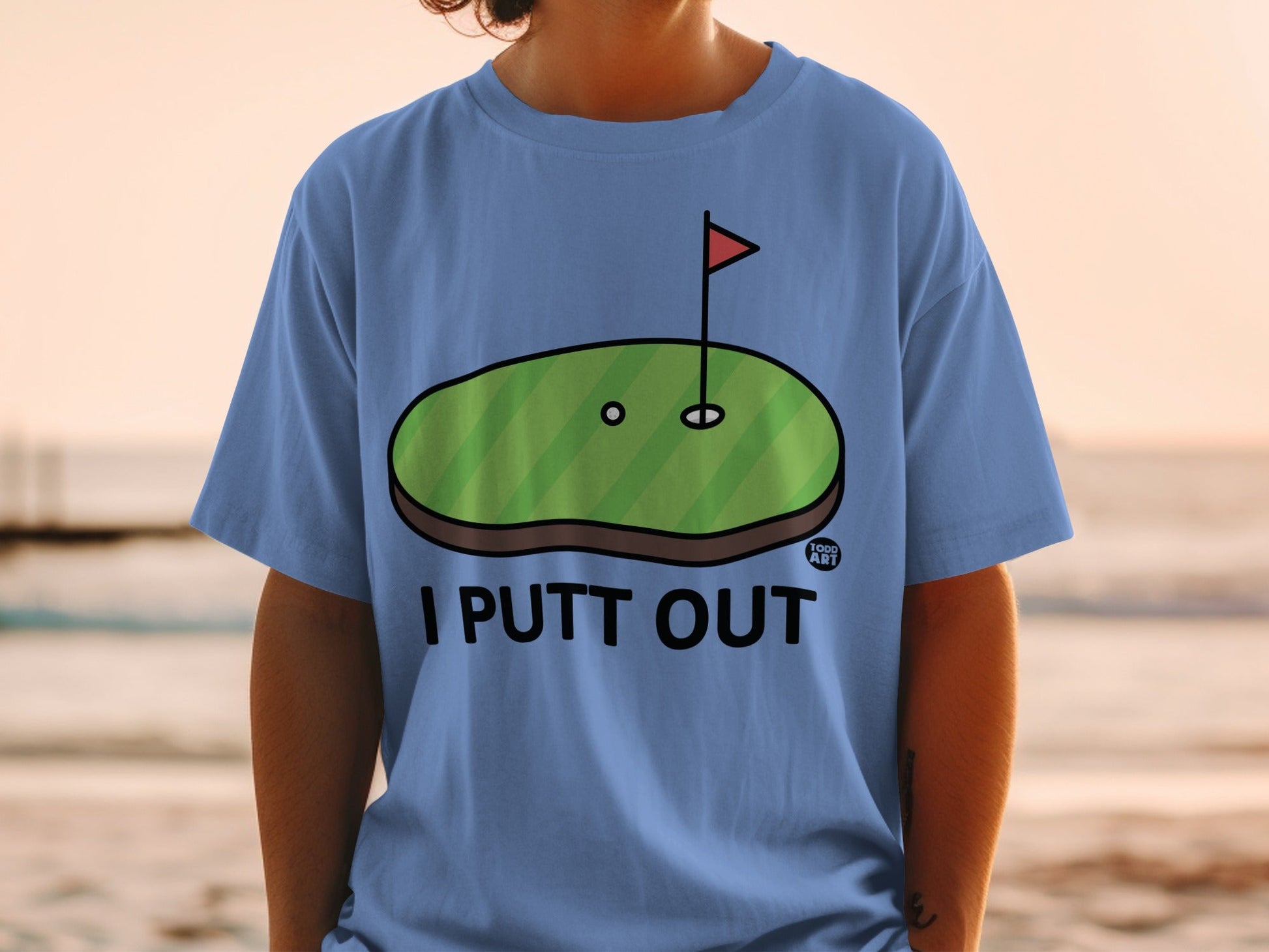 Blue t-shirt with cartoon golf green and "I PUTT OUT" text.