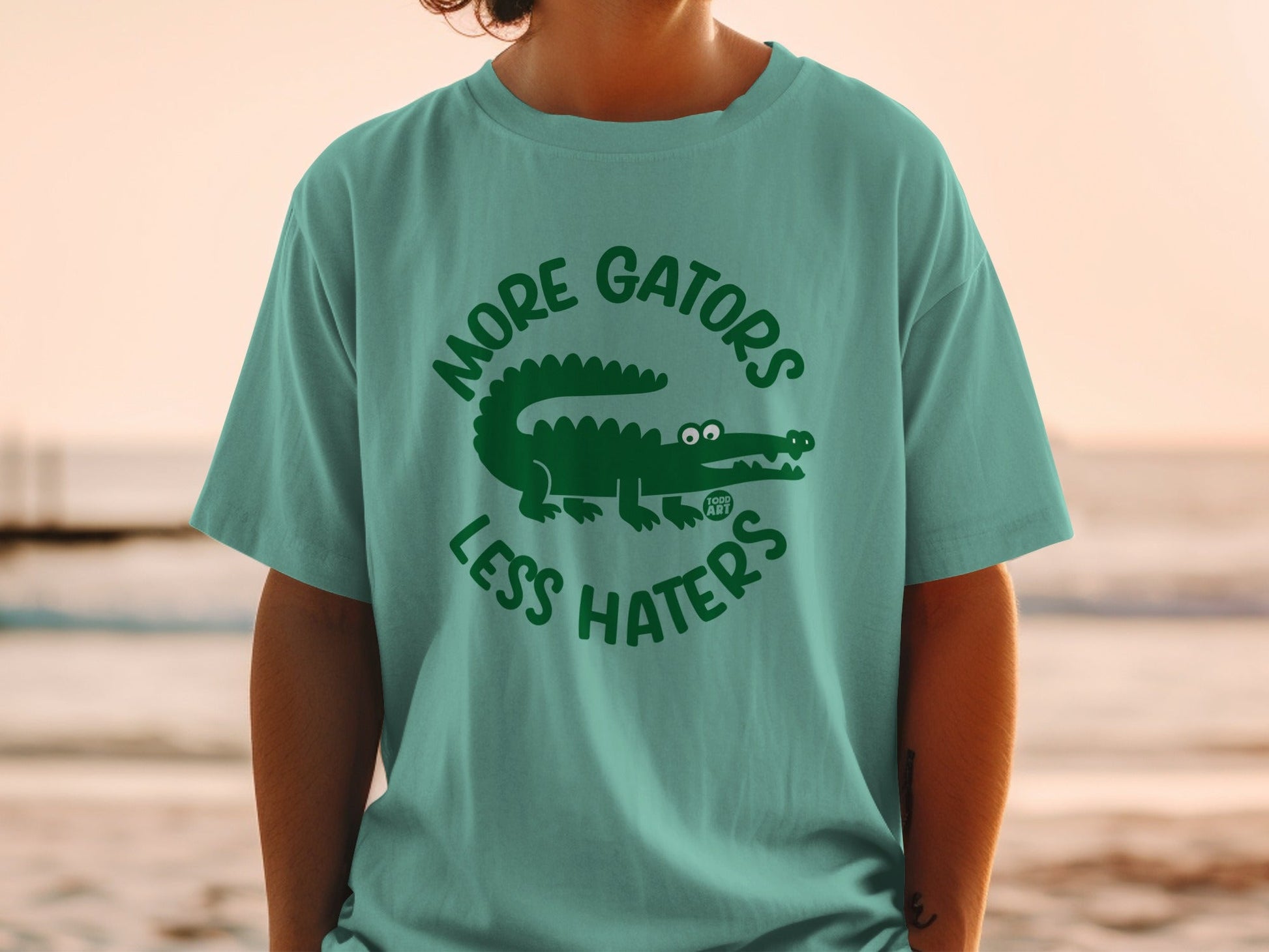 Teal t-shirt with "More Gators Less Haters" and a cartoon alligator graphic.
