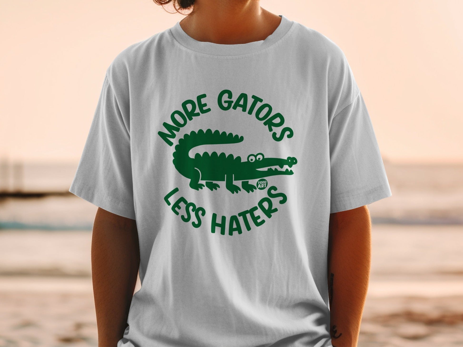 White t-shirt with green alligator graphic and "MORE GATORS LESS HATERS" text.