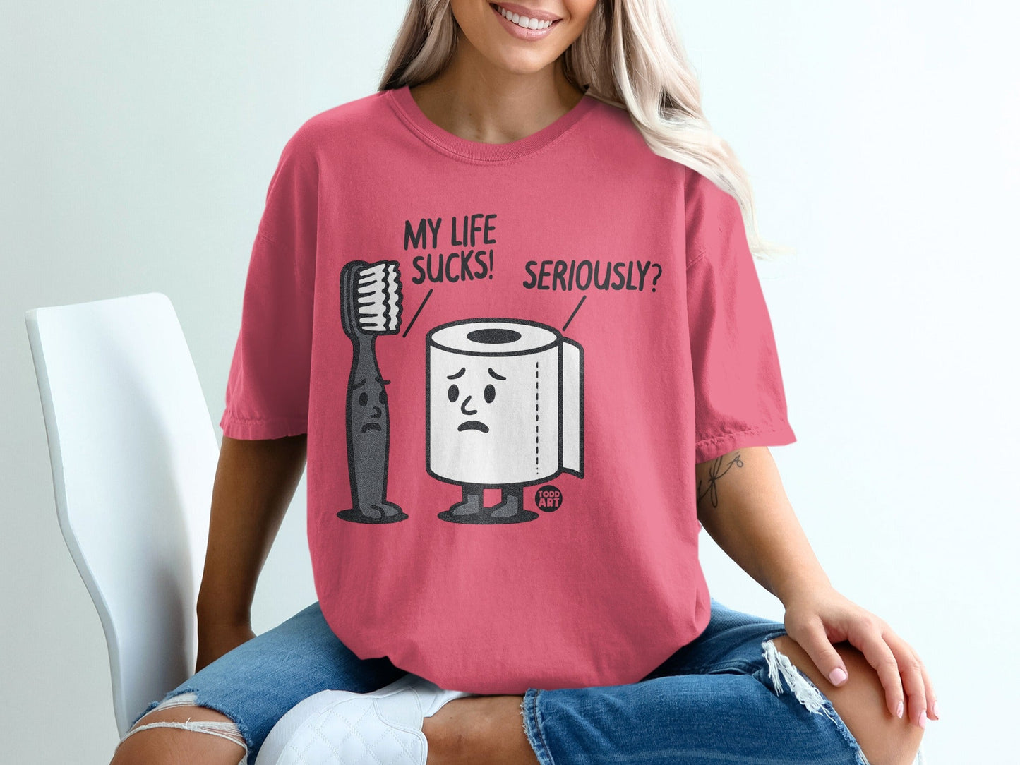 Pink t-shirt with cartoon toothbrush and toilet paper asking "MY LIFE SUCKS! SERIOUSLY?".
