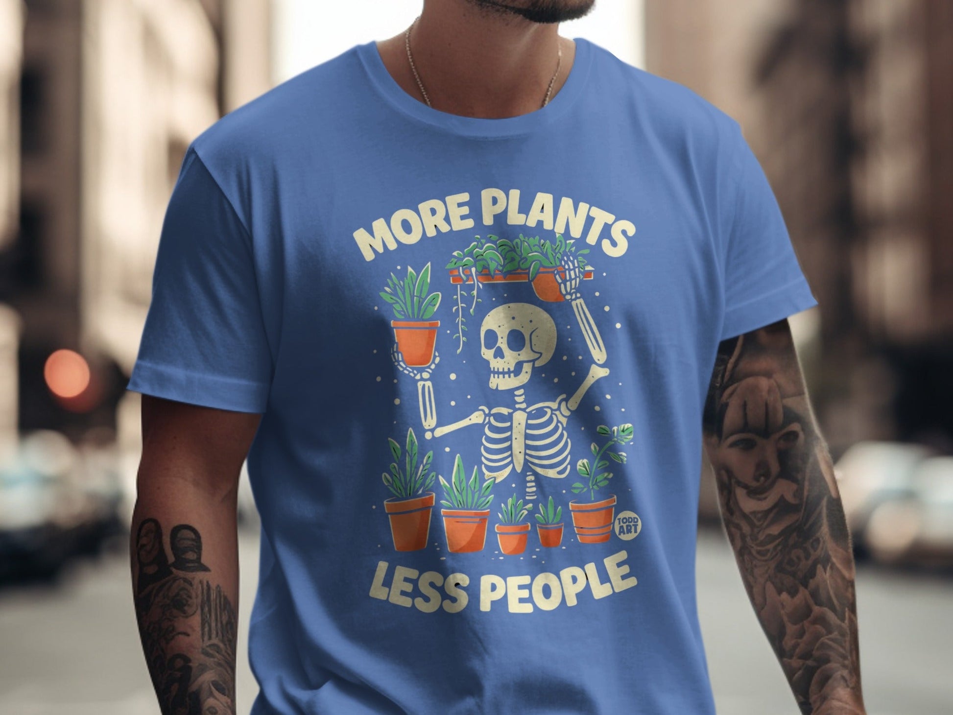 Skeleton holding plants with text "More Plants Less People" on a blue t-shirt.