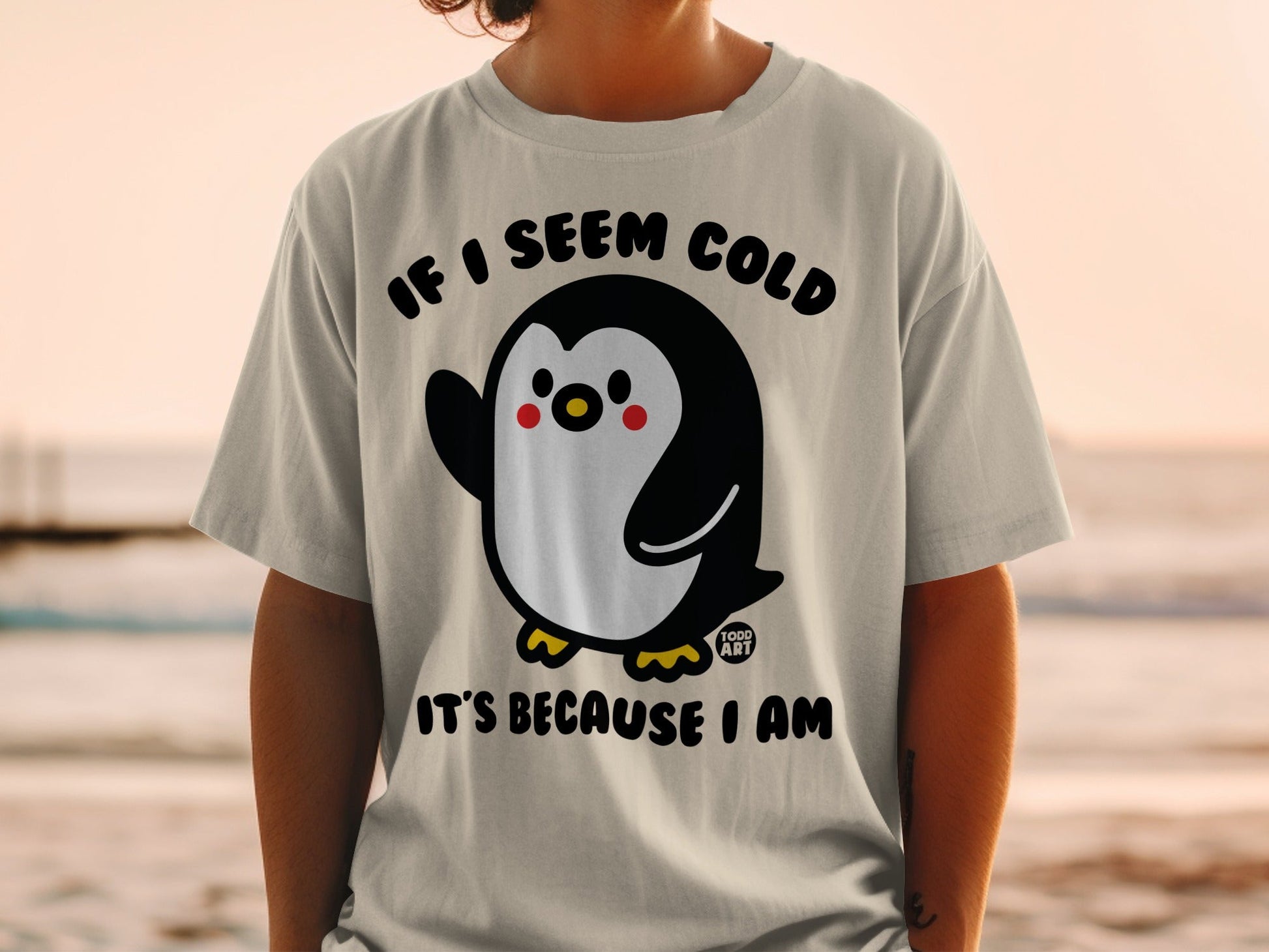 T-shirt with cartoon penguin waving, text "IF I SEEM COLD IT'S BECAUSE I AM".