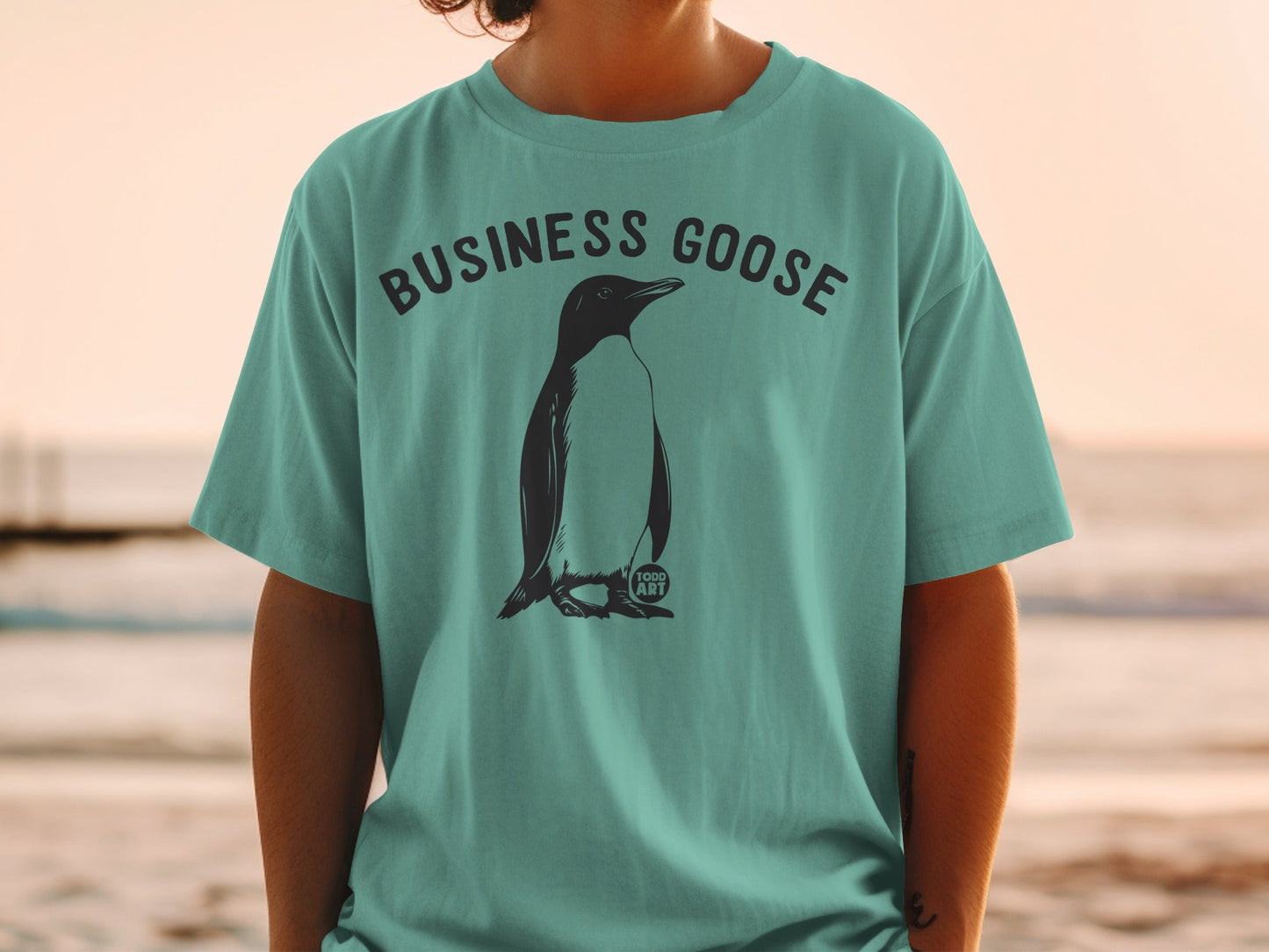 Teal t-shirt with "BUSINESS GOOSE" text and a penguin graphic.