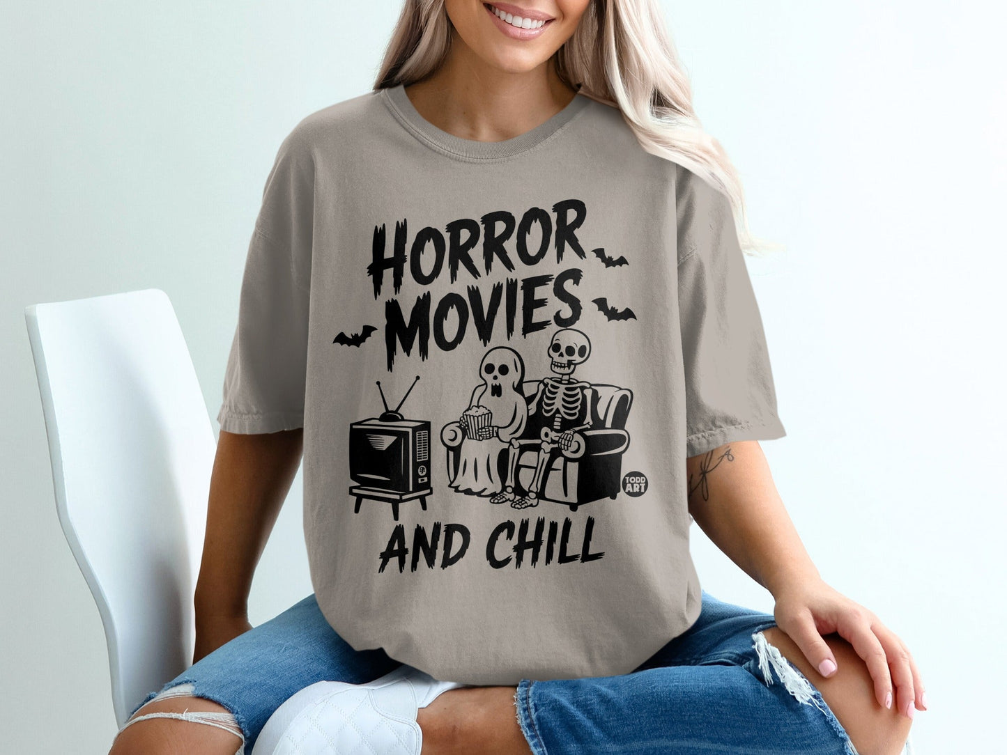 T-shirt with "Horror Movies And Chill" text, a skeleton, and a ghost watching TV.