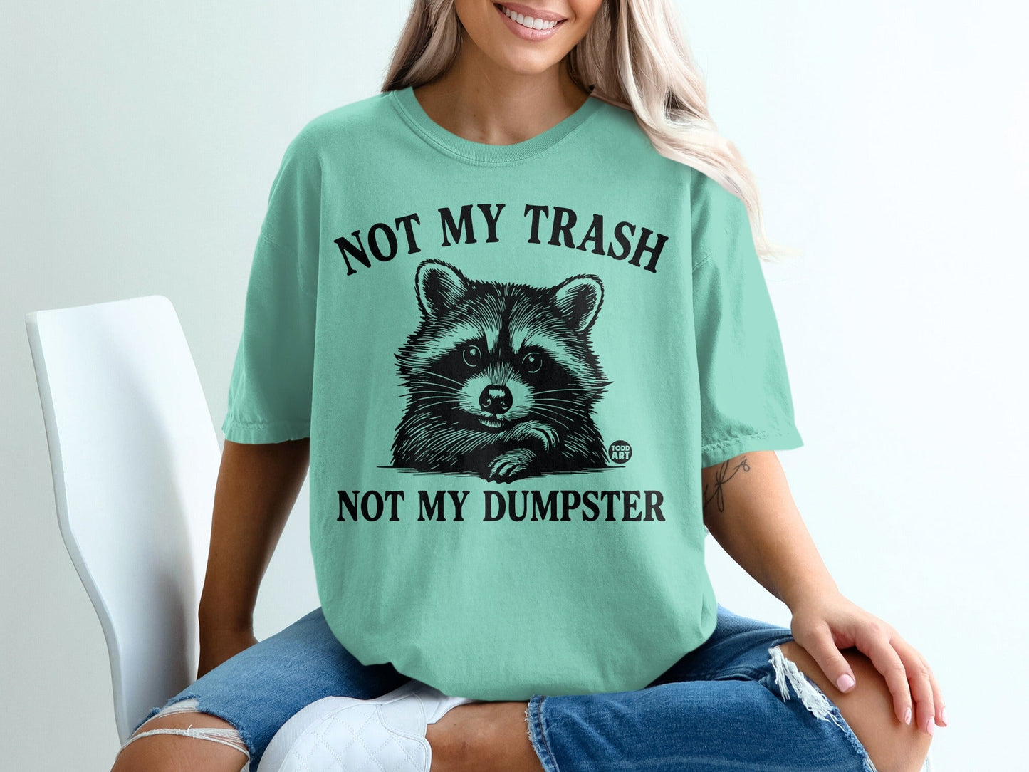 Mint t-shirt with raccoon graphic and text "NOT MY TRASH NOT MY DUMPSTER".