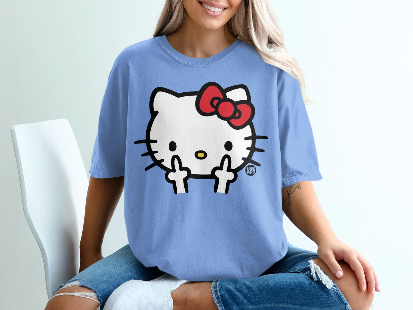 Hello Kitty wearing a red bow giving the middle finger on a light blue t-shirt.