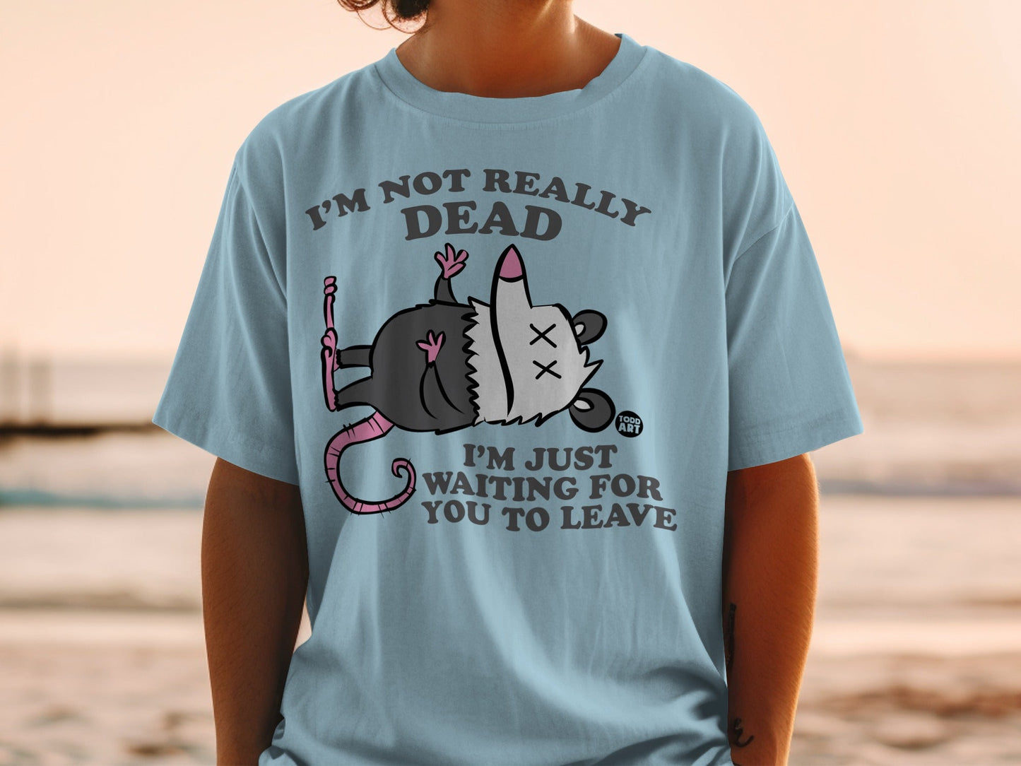 T-shirt with a cartoon possum and text "I'M NOT REALLY DEAD I'M JUST WAITING FOR YOU TO LEAVE".