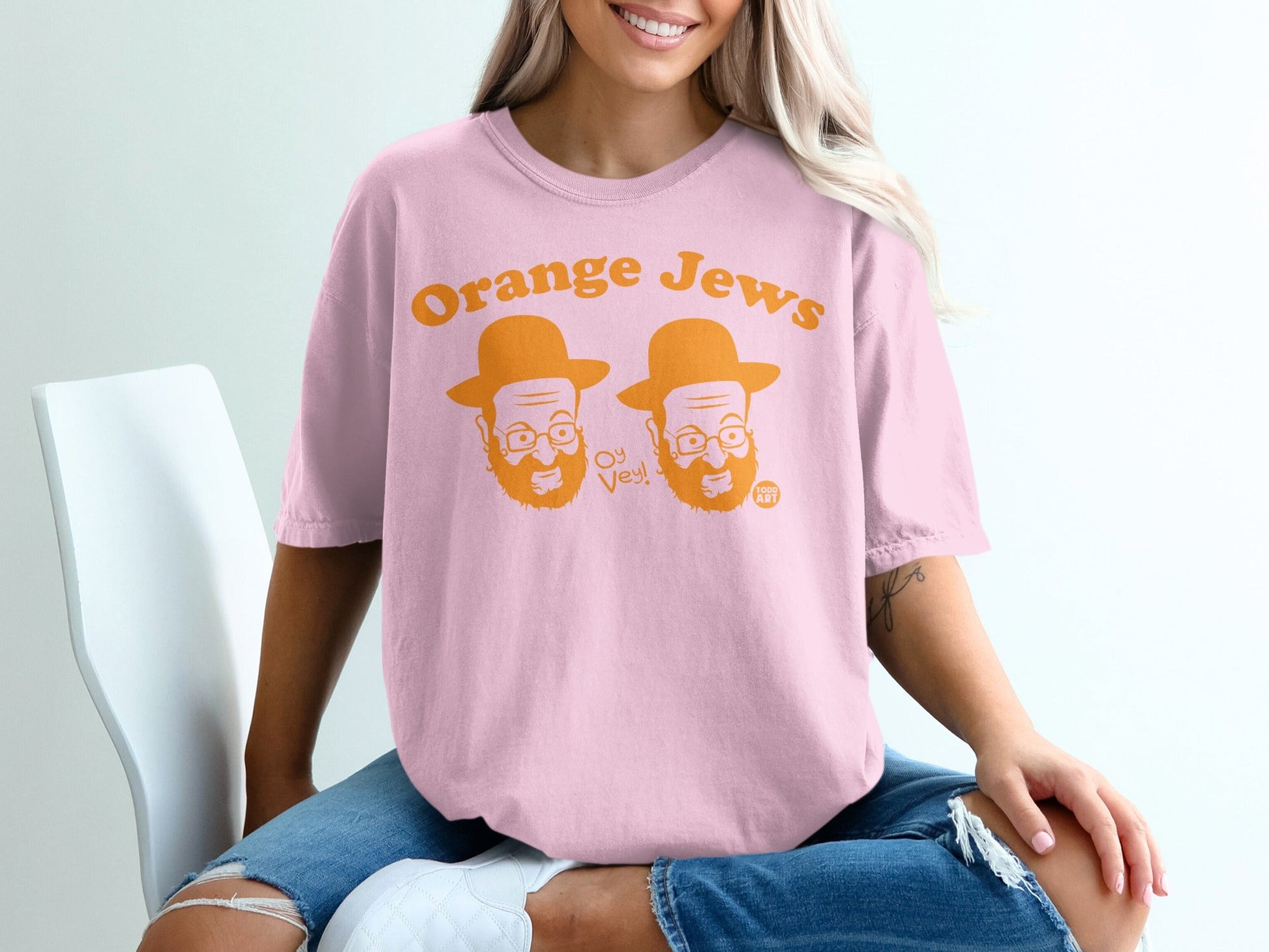 Pink t-shirt with "Orange Jews" and cartoon faces, worn by a person.