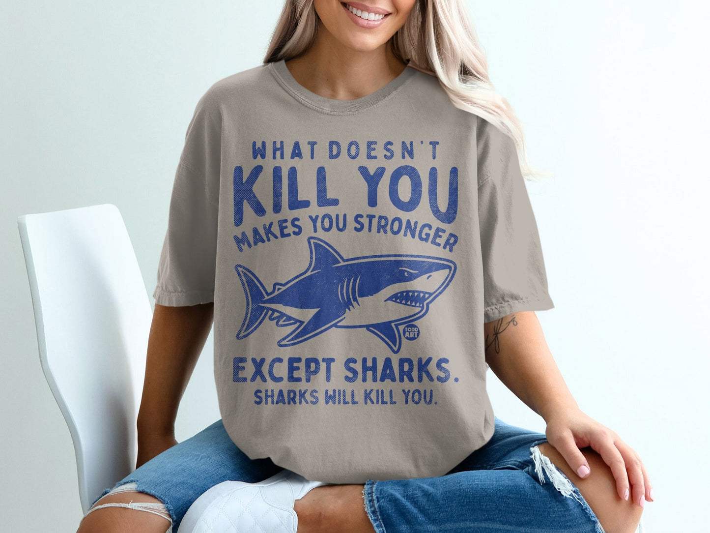 T-shirt with shark graphic and text "What doesn't kill you makes you stronger, except sharks. Sharks will kill you."