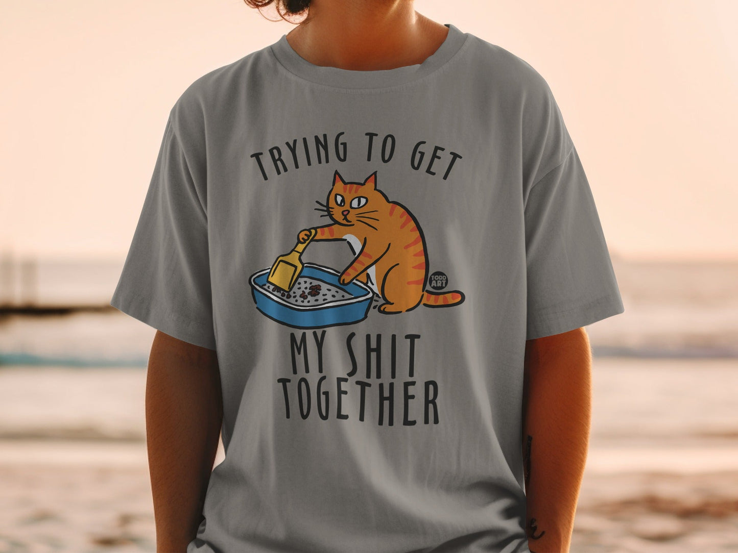 Gray t-shirt with orange cat scooping a litter box, text reads "Trying to get my shit together."