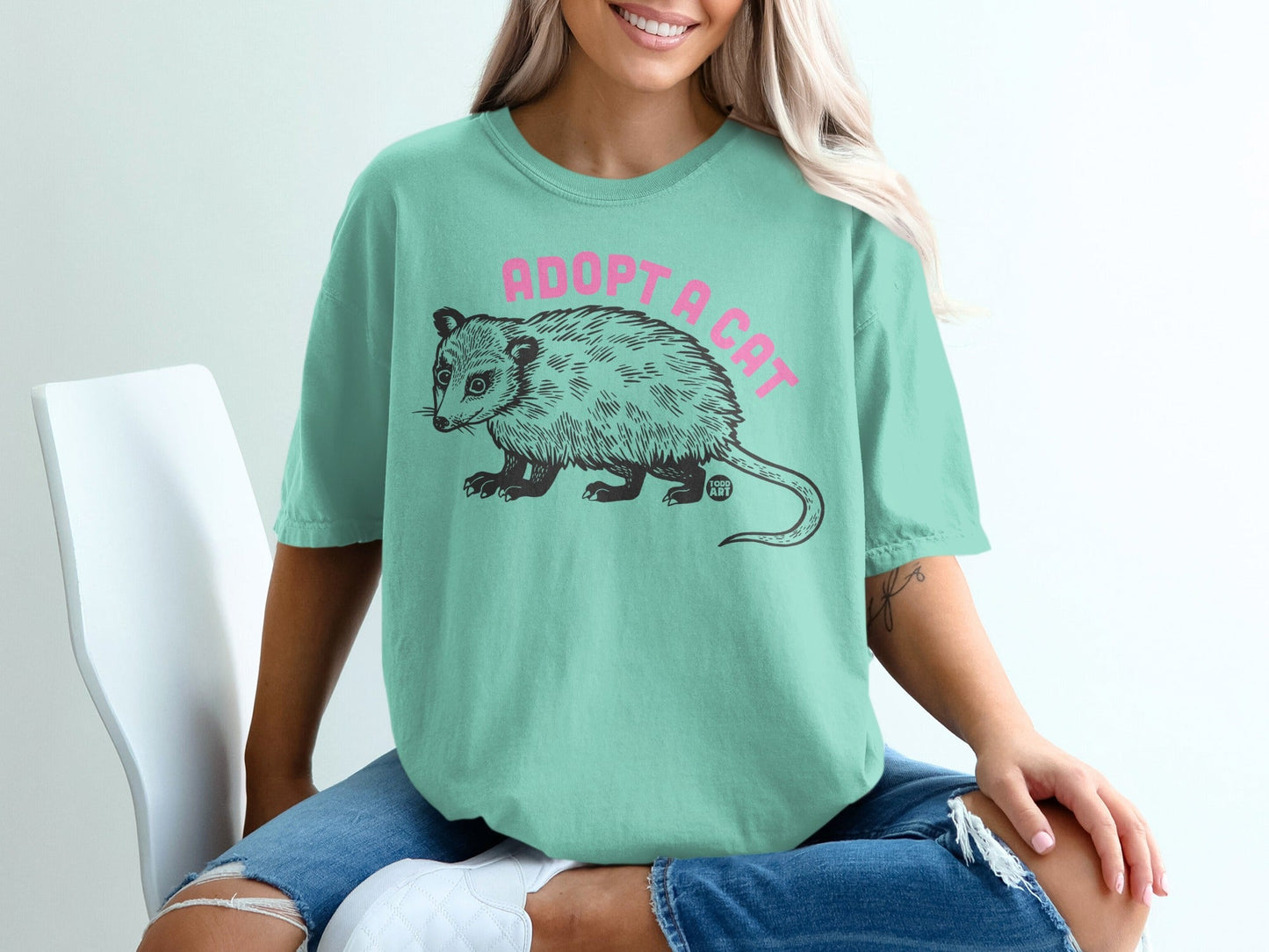 Mint t-shirt with "Adopt a Cat" text and possum graphic.