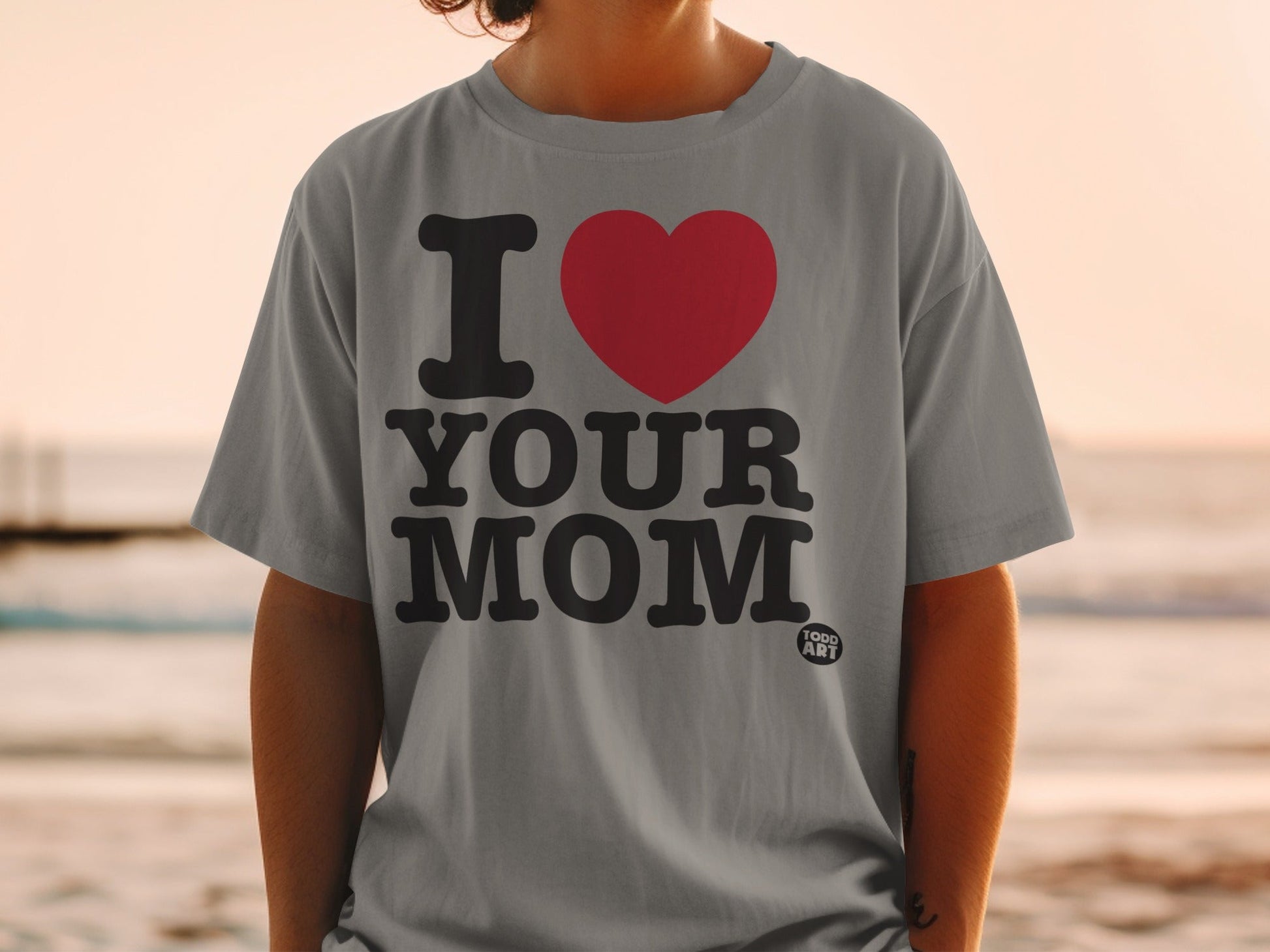 Grey t-shirt with black text "I ‚ù§Ô∏è YOUR MOM" and a small "GOOD ART" logo.