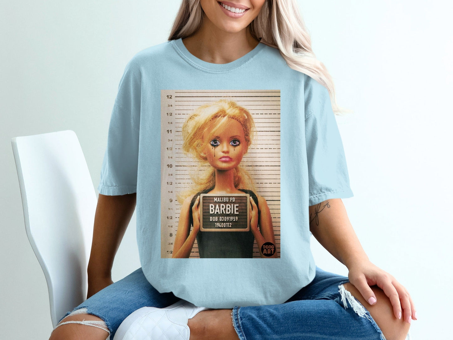 Light blue t-shirt with a Barbie mugshot graphic featuring "MALIBU PD BARBIE" text.