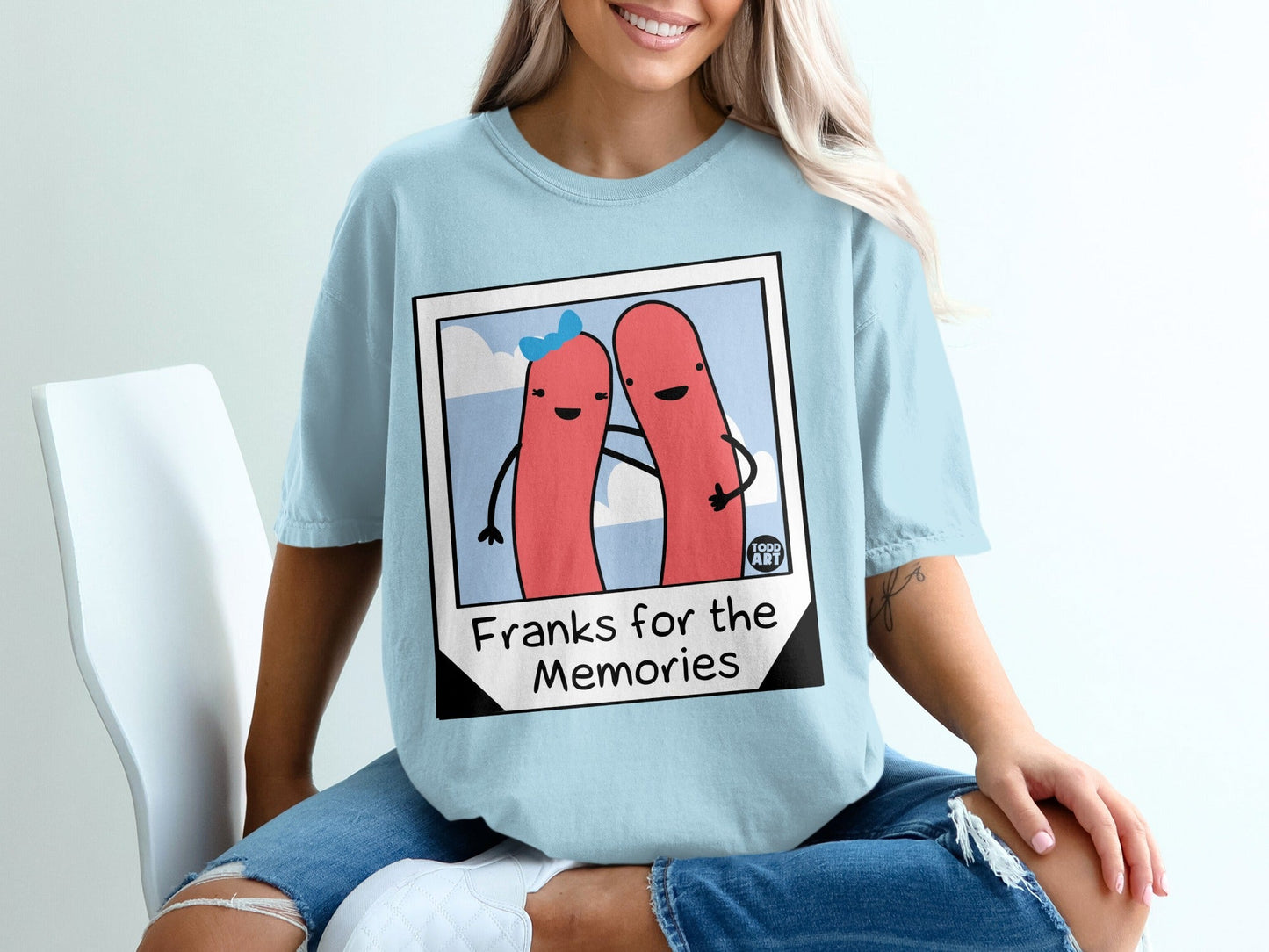 Light blue t-shirt with cartoon hot dogs and text "Franks for the Memories".