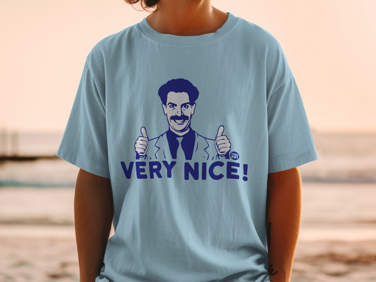 Light blue t-shirt with Borat character giving two thumbs up and "VERY NICE!" text.