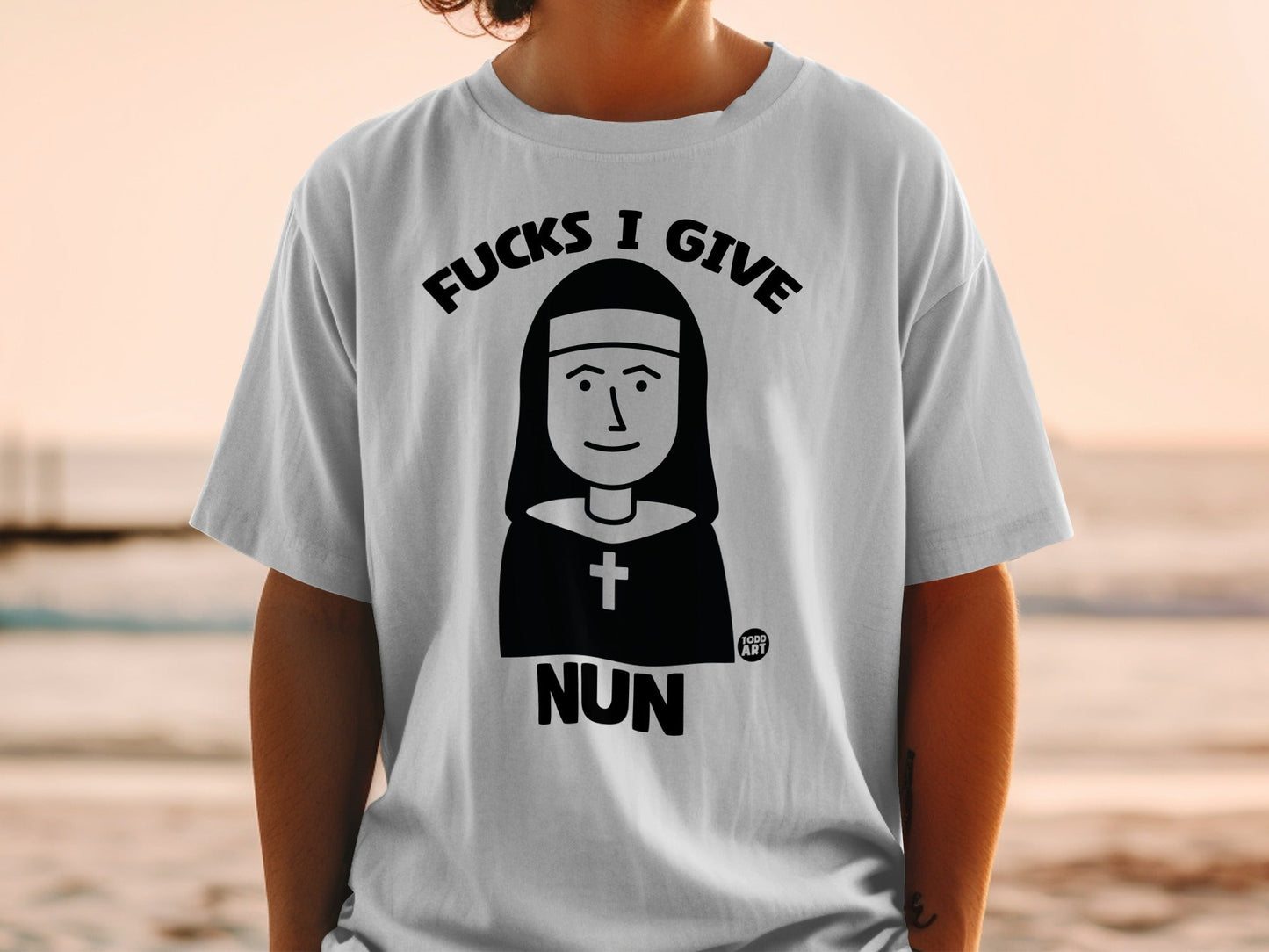 Black and white graphic on a white t-shirt: a nun illustration with "NUN" text.