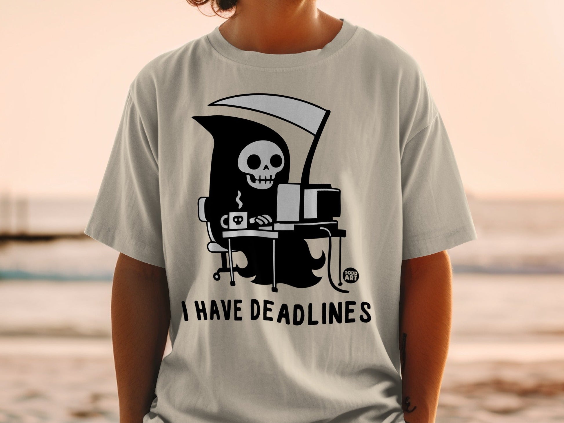 Grim Reaper sitting at a computer with text "I HAVE DEADLINES" on a t-shirt.