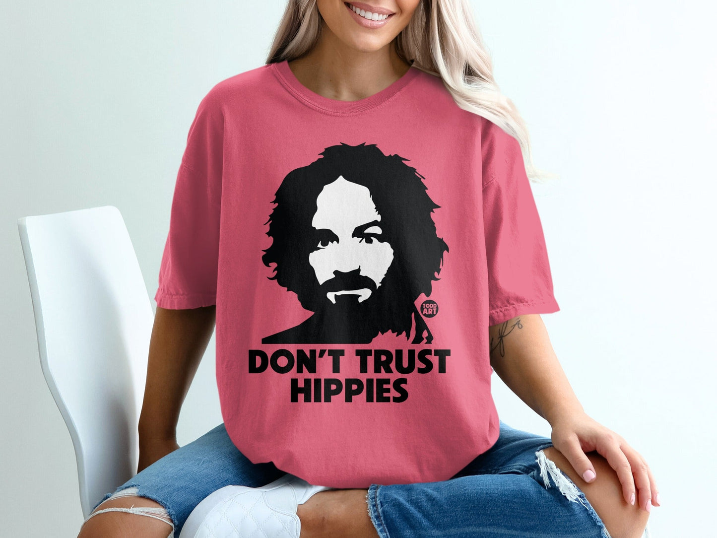 Woman wearing a pink t-shirt with a graphic of a man and text "DON'T TRUST HIPPIES".