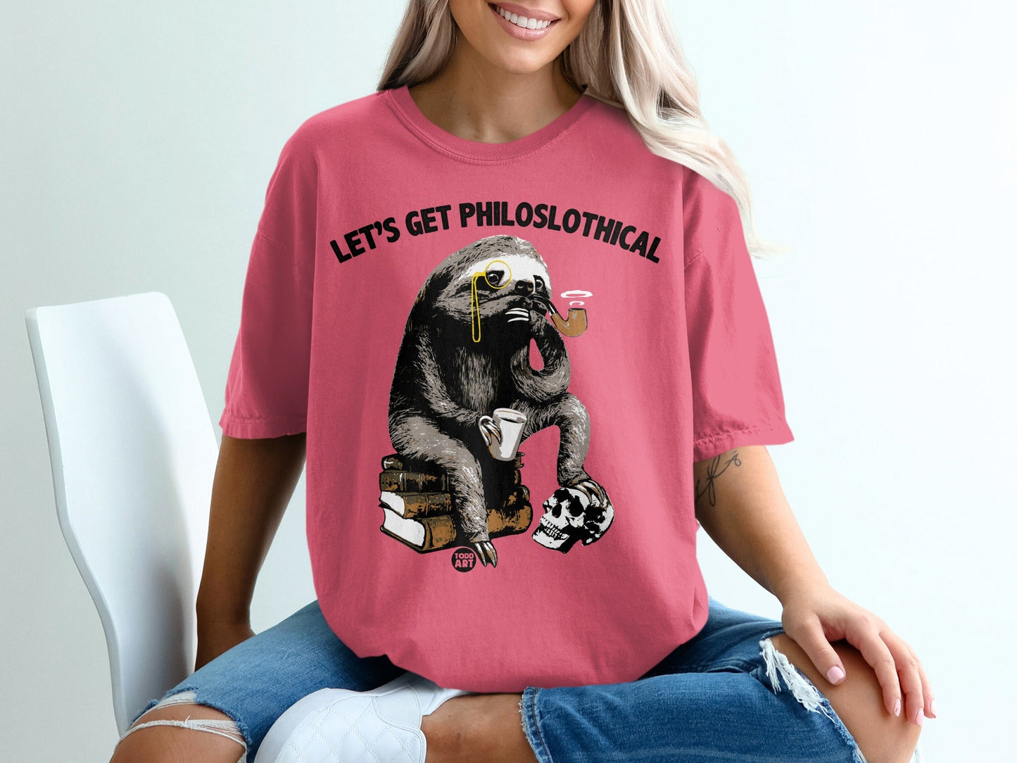 Sloth wearing monocle, smoking pipe, sitting on books with skull. "Let's Get PhiloSLOTHical" text.