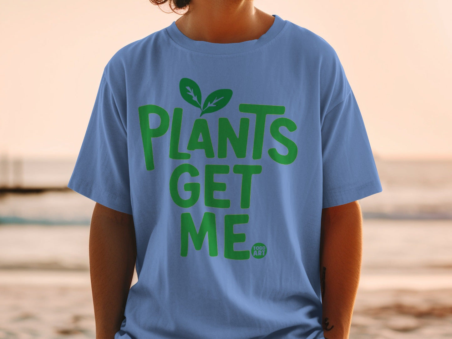 Blue t-shirt with green text "PLANTS GET ME" and a small logo.