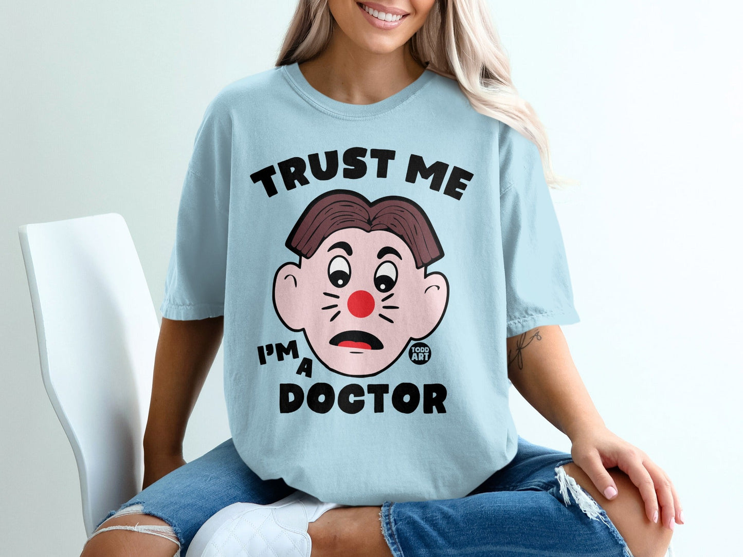 Light blue t-shirt with "Trust Me I'm A Doctor" text and clown face graphic.