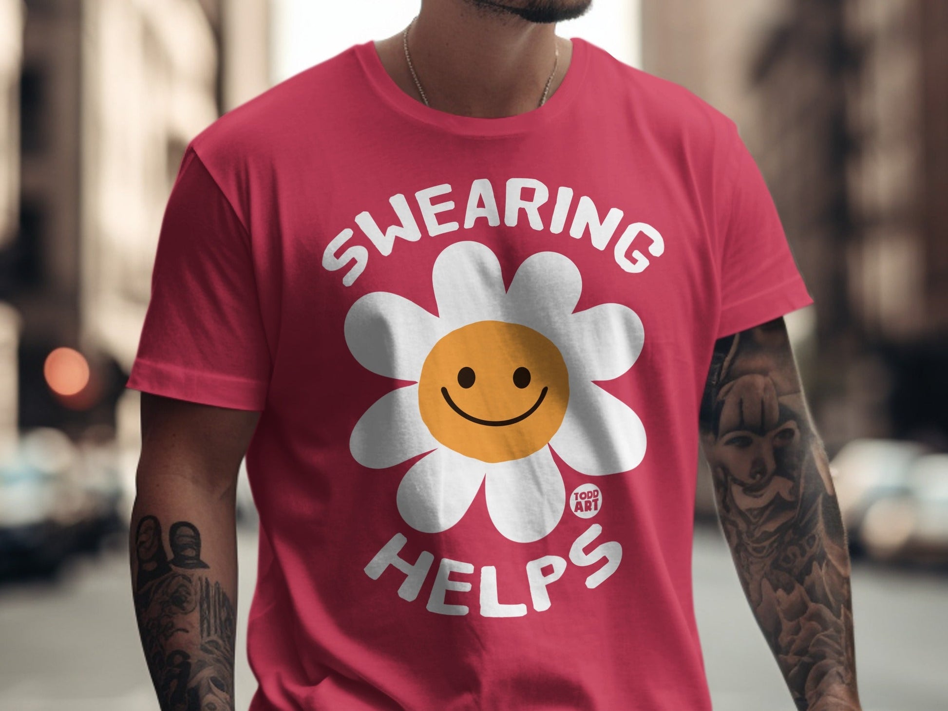 Red t-shirt with white text "SWEARING HELPS" and a smiling daisy graphic.