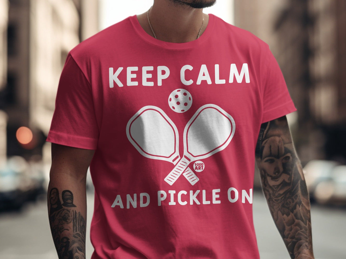 Red t-shirt with "KEEP CALM AND PICKLE ON" and pickleball paddles.