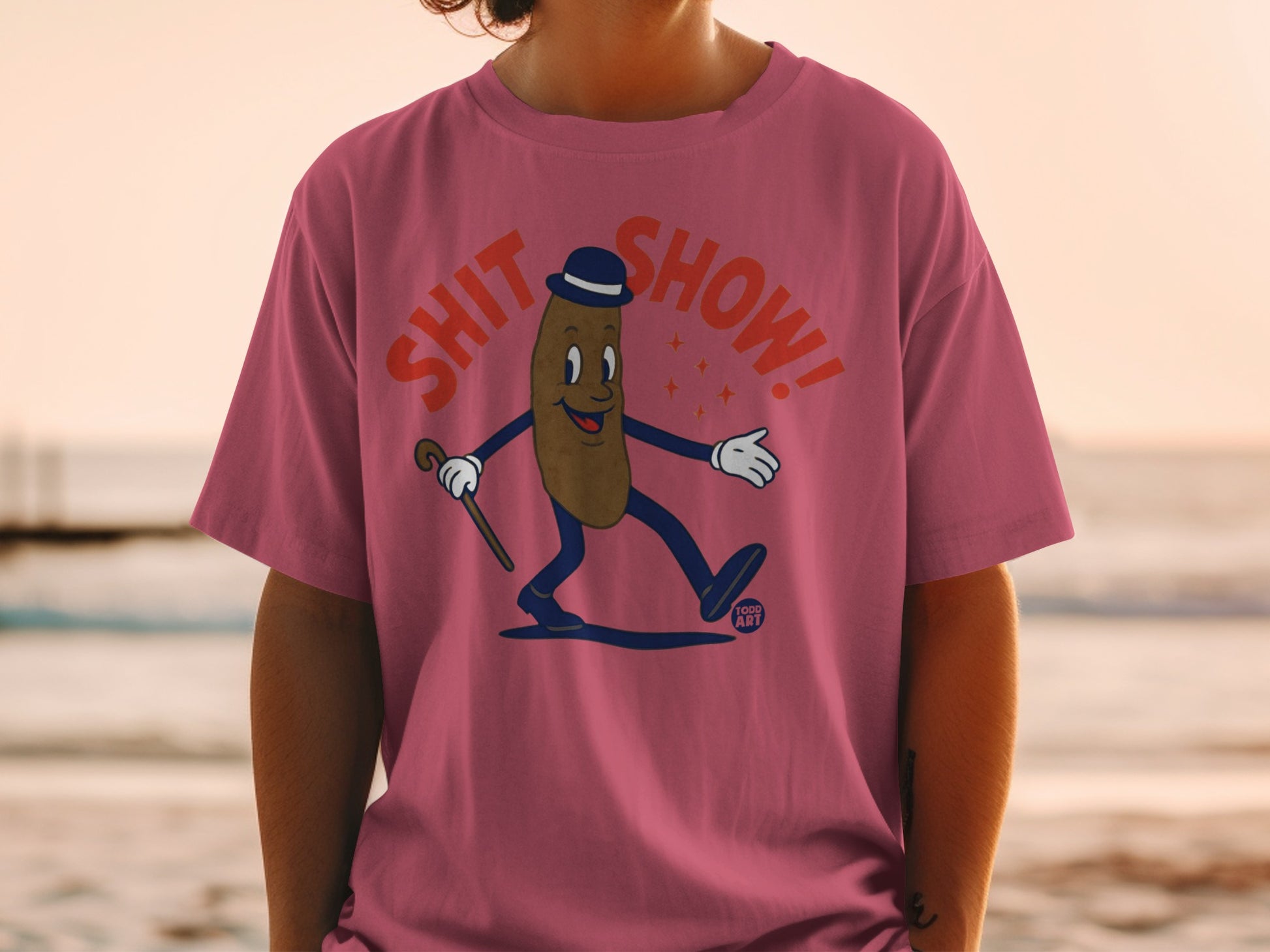 Cartoon poop character in a bowler hat and cane on pink t-shirt.
